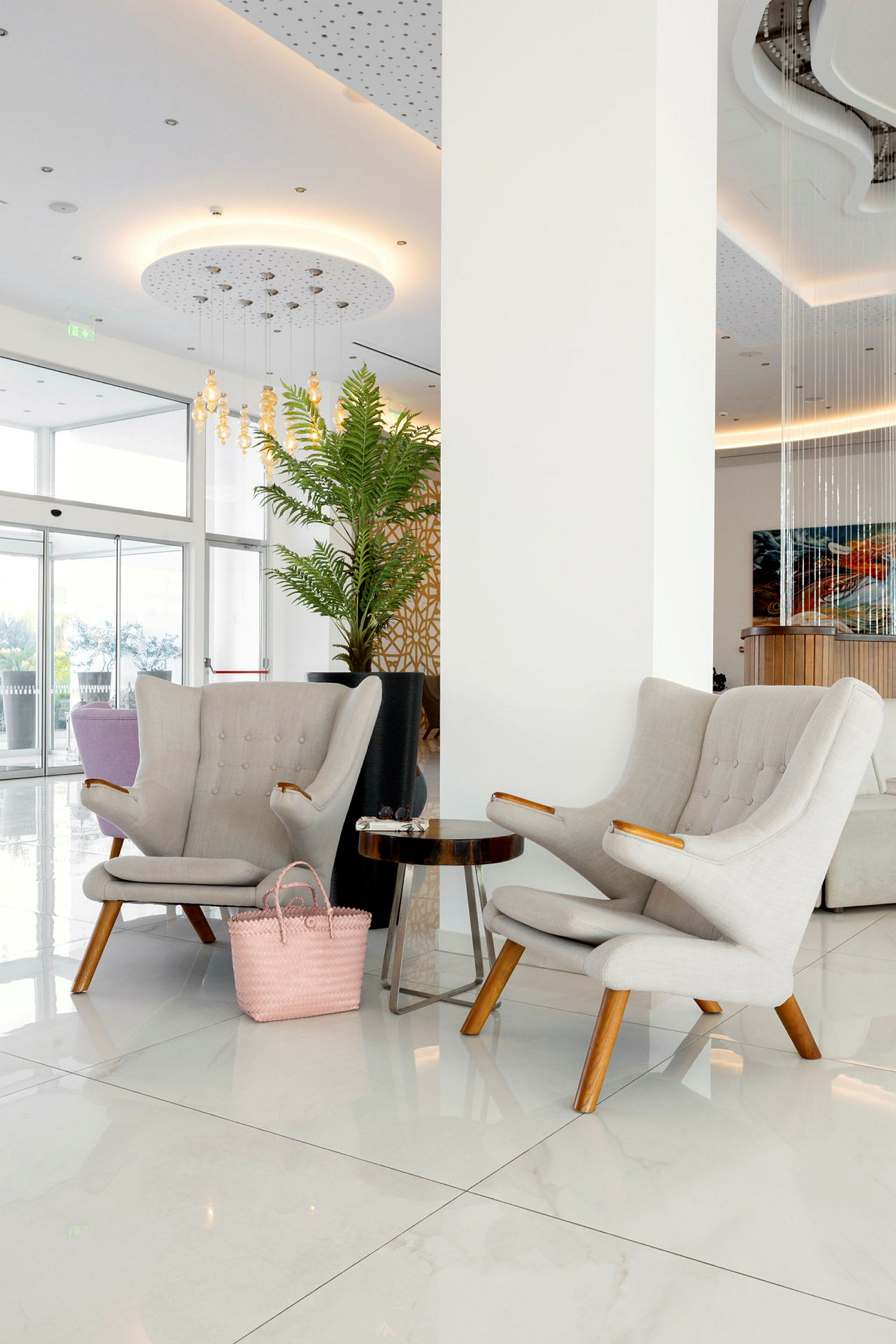 To lyse stoler og et sidebord i et moderne hotellobbyområde. (AI-generert tekst)