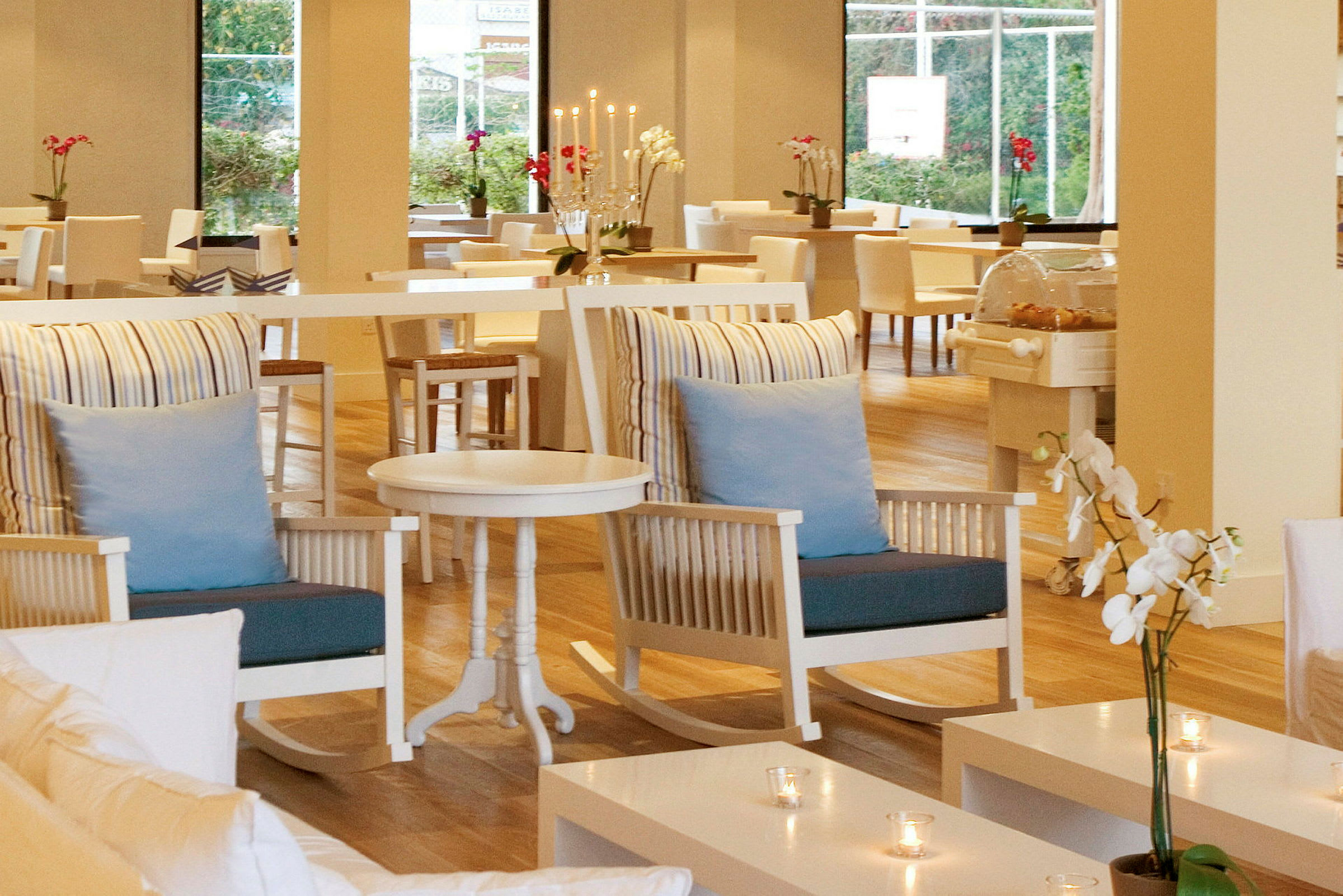 Interiør av en restaurant med lyse møbler, blomster og dekorasjoner. (AI-generert tekst)