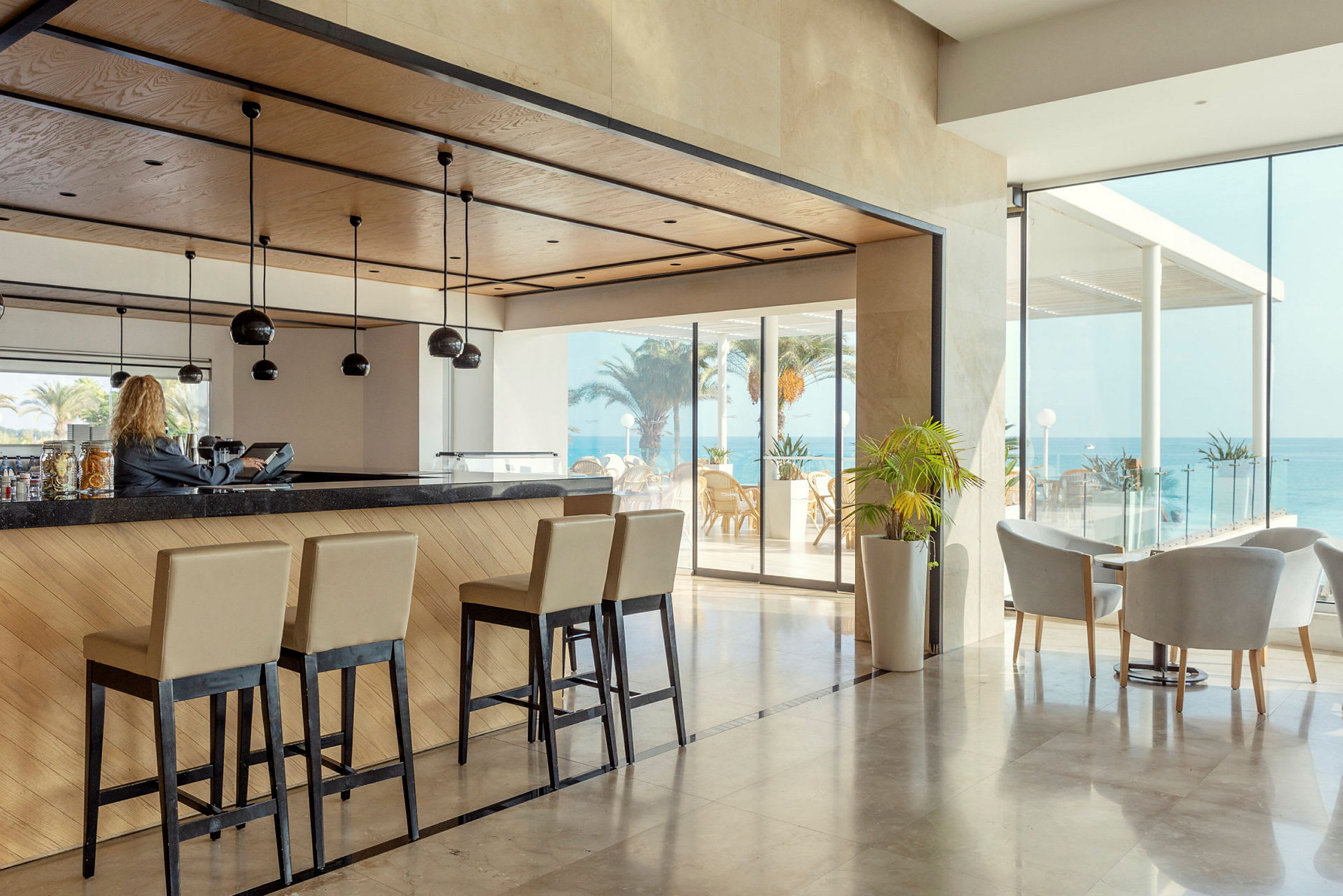 Hotellbar med høye stoler og utsikt mot havet. (AI-generert tekst)