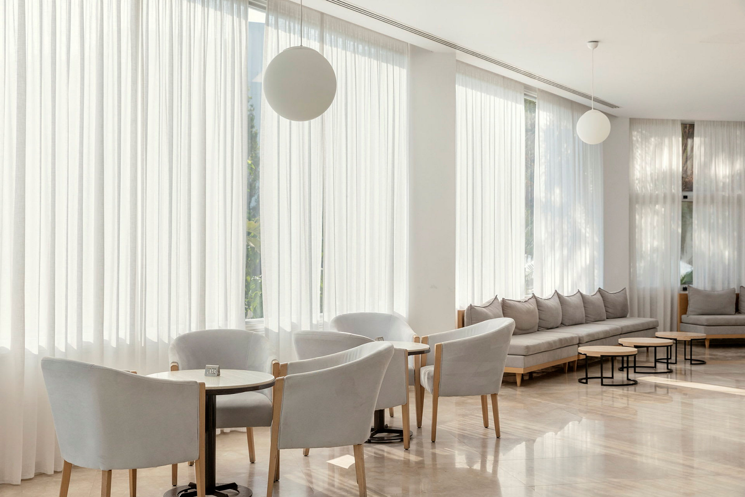 En moderne lounge med stoler, små bord og sofaer i lyse farger. (AI-generert tekst)