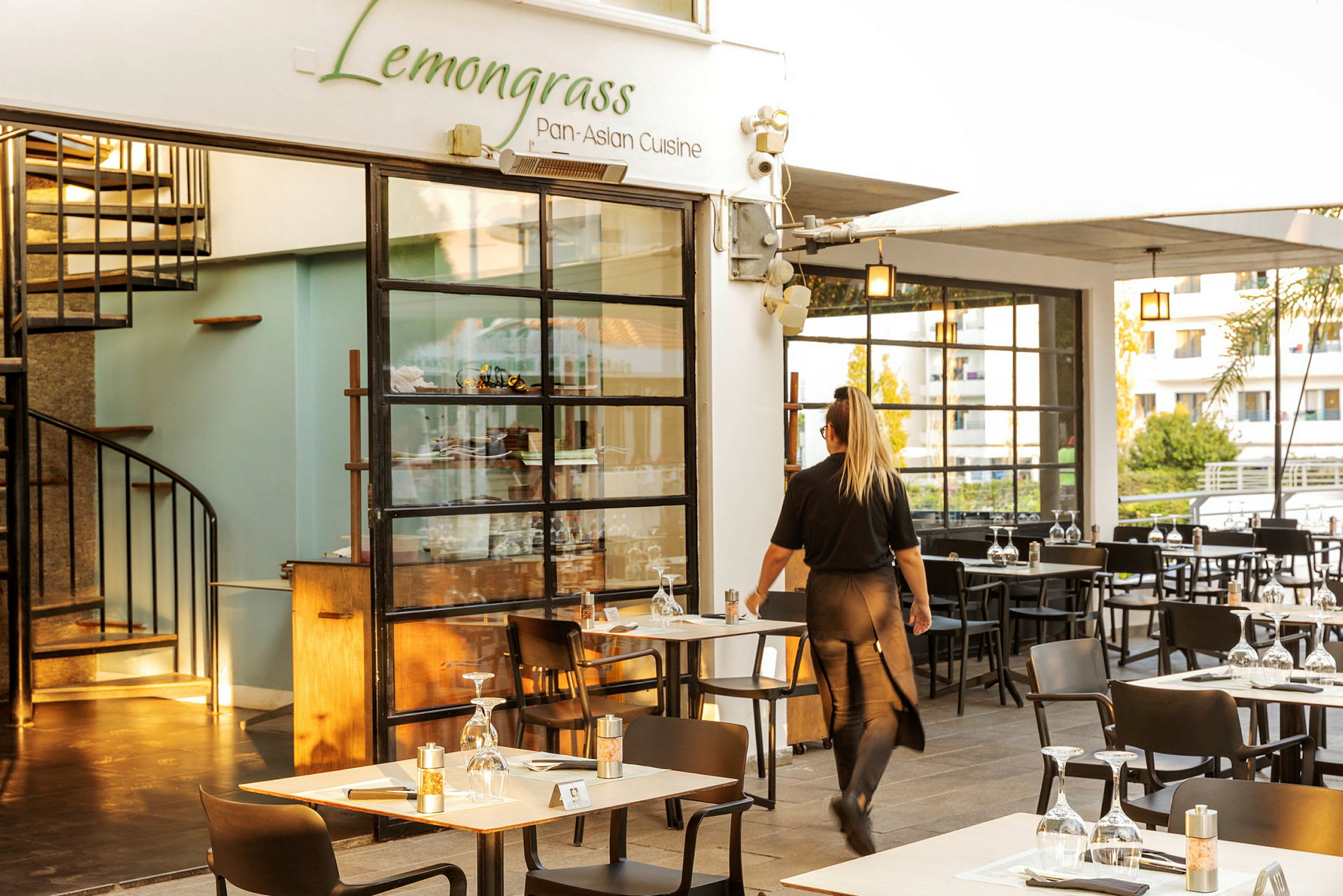 Restaurant med navnet Lemongrass og en servitør som går mellom bordene. (AI-generert tekst)