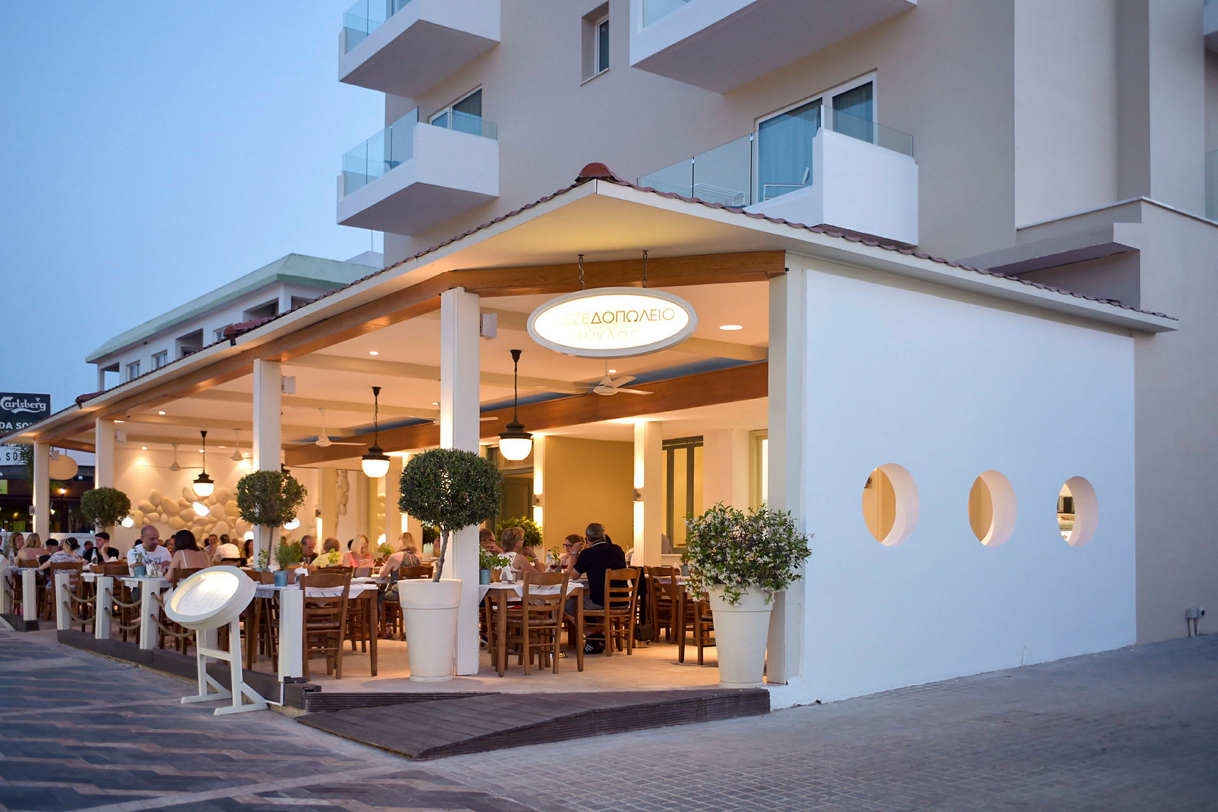 Uteområde til en restaurant med gjester som spiser ved bord om kvelden. (AI-generert tekst)
