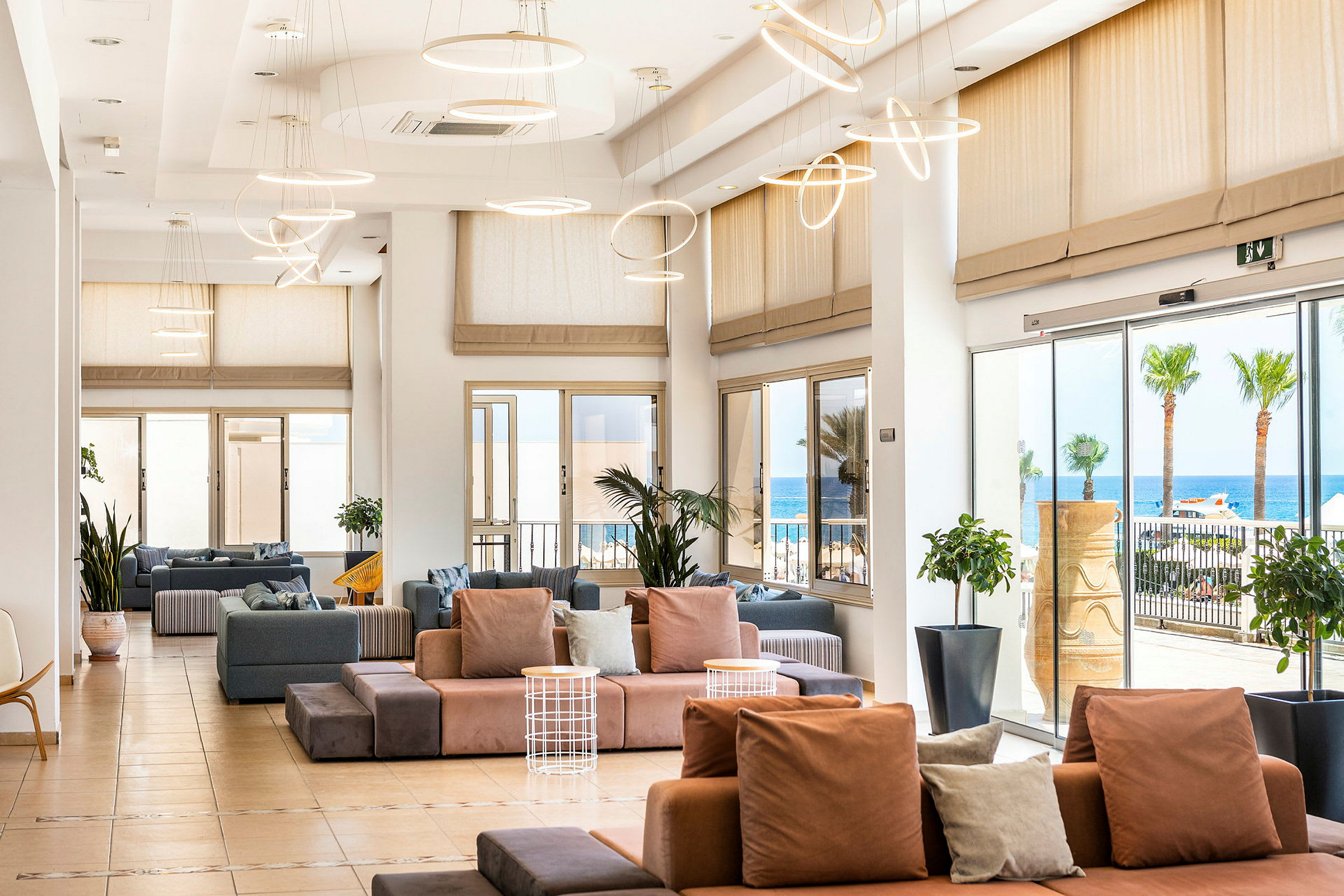 Lys og romslig loungedel med moderne sofaer, store vinduer og utsikt mot havet. (AI-generert tekst)