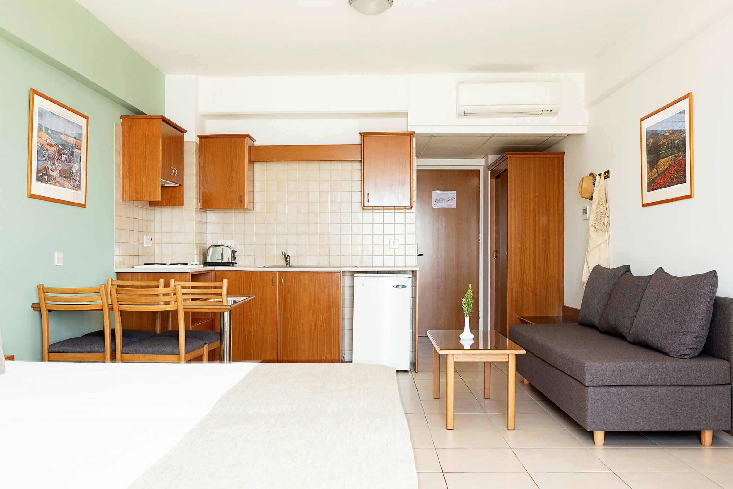 Et hotellstudio med kjøkken, spisebord og sittegruppe. (AI-generert tekst)