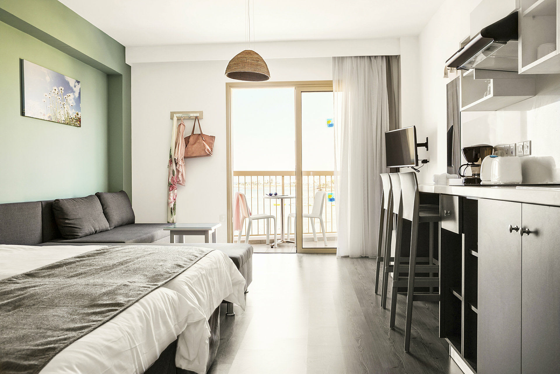 Et moderne hotellrom med sovesofa, seng, kjøkkenutstyr og balkong med utsikt. (AI-generert tekst)