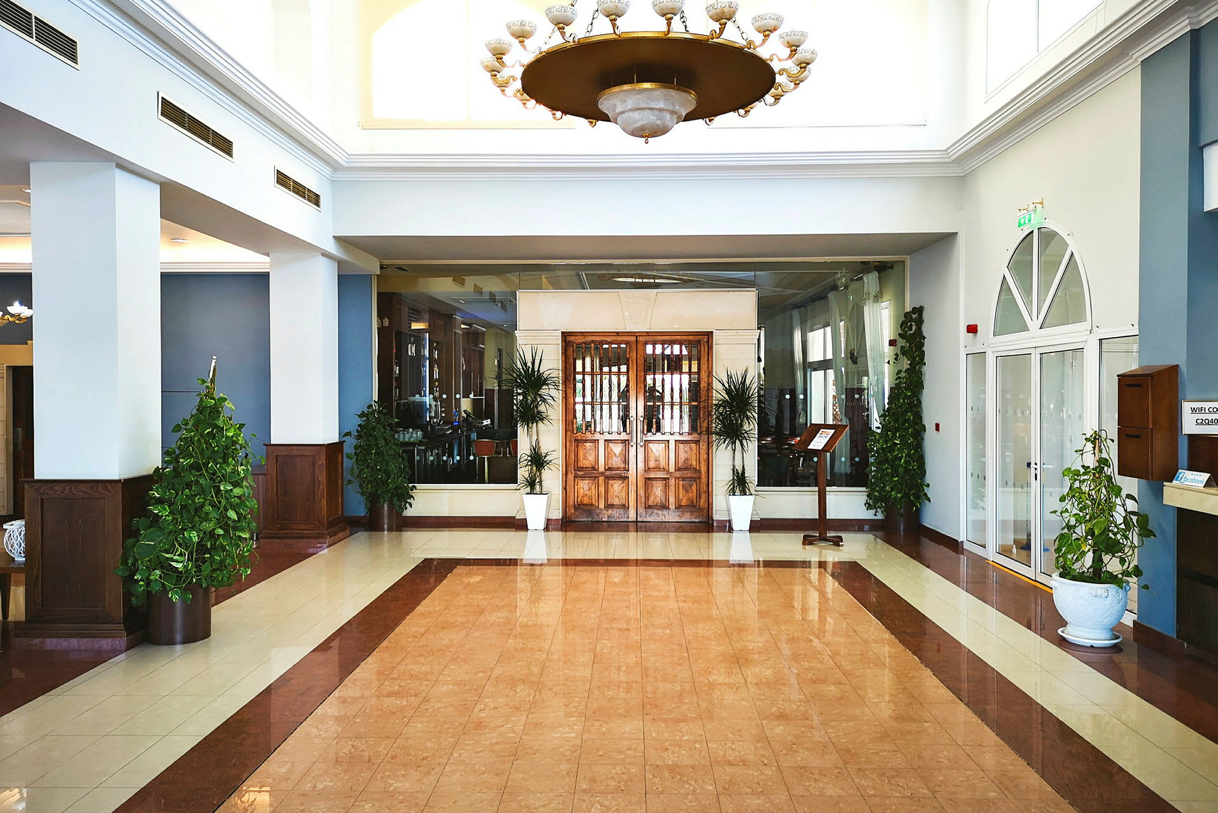 En hotellobby med tredetaljer, store glassdører og grønne planter. (AI-generert tekst)