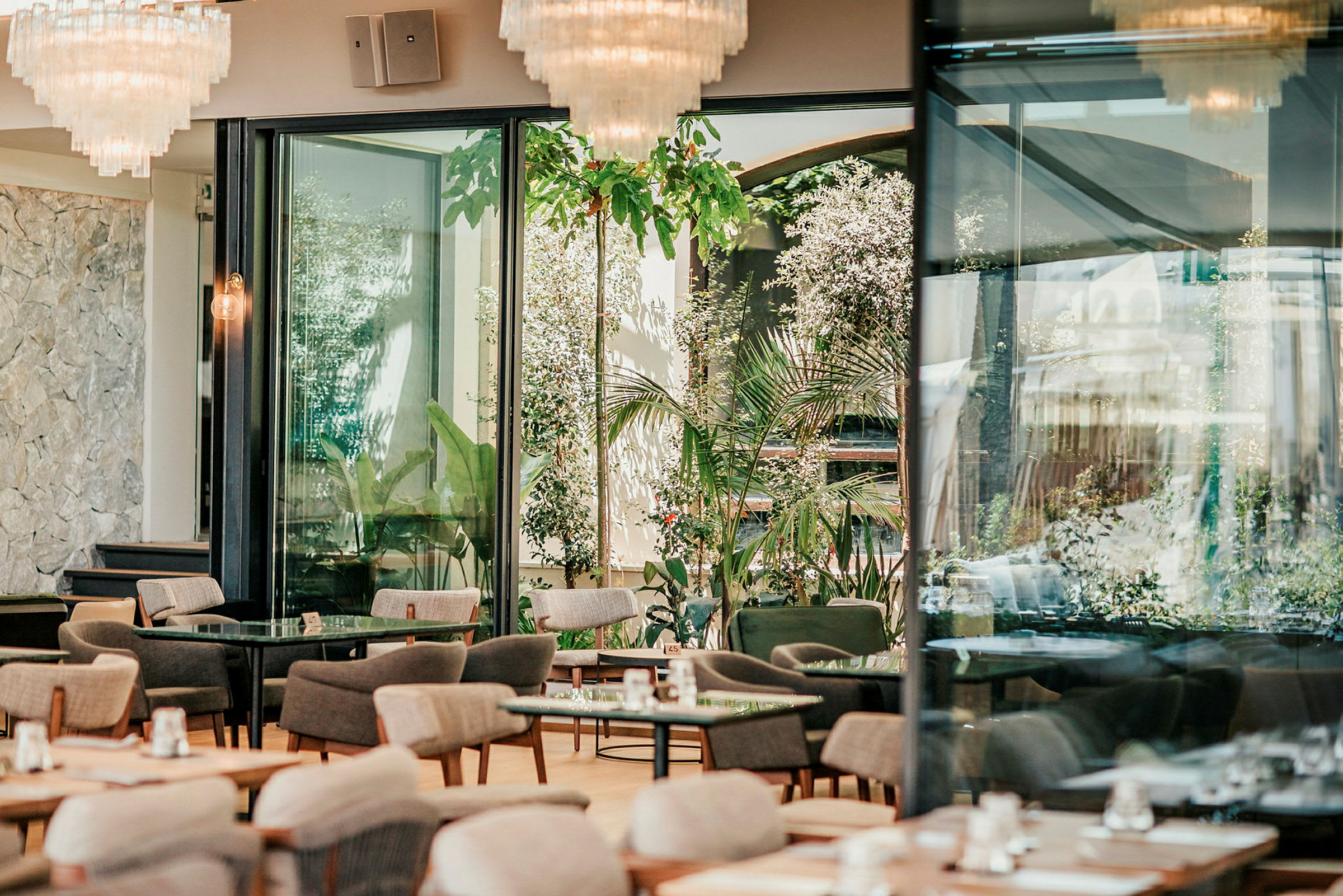 En moderne, lyst restaurant med store vinduer og grøntområder utenfor. (AI-generert tekst)