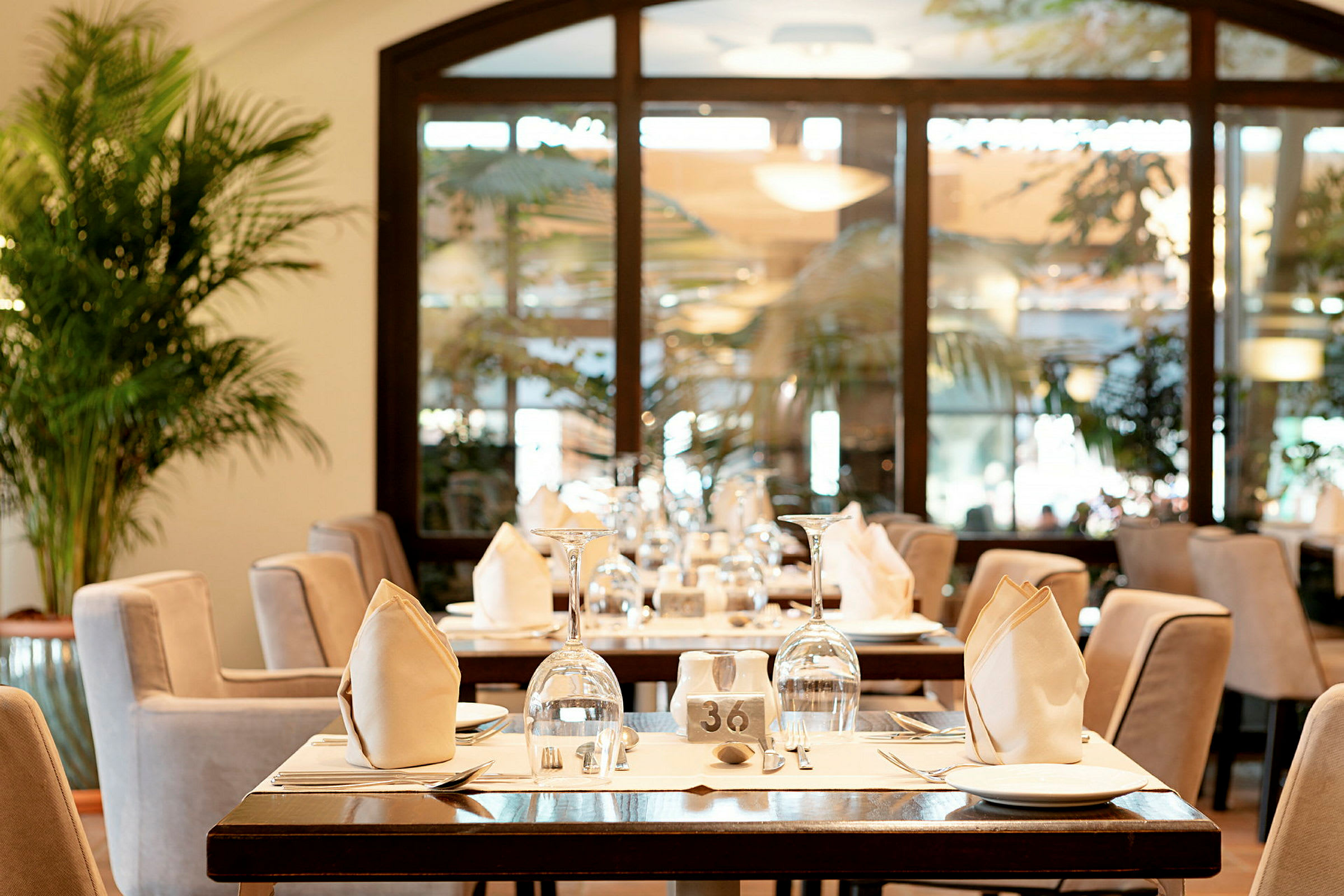 Et restaurantbord med elegant borddekking som inkluderer glass, tallerkener og brettede servietter. (AI-generert tekst)