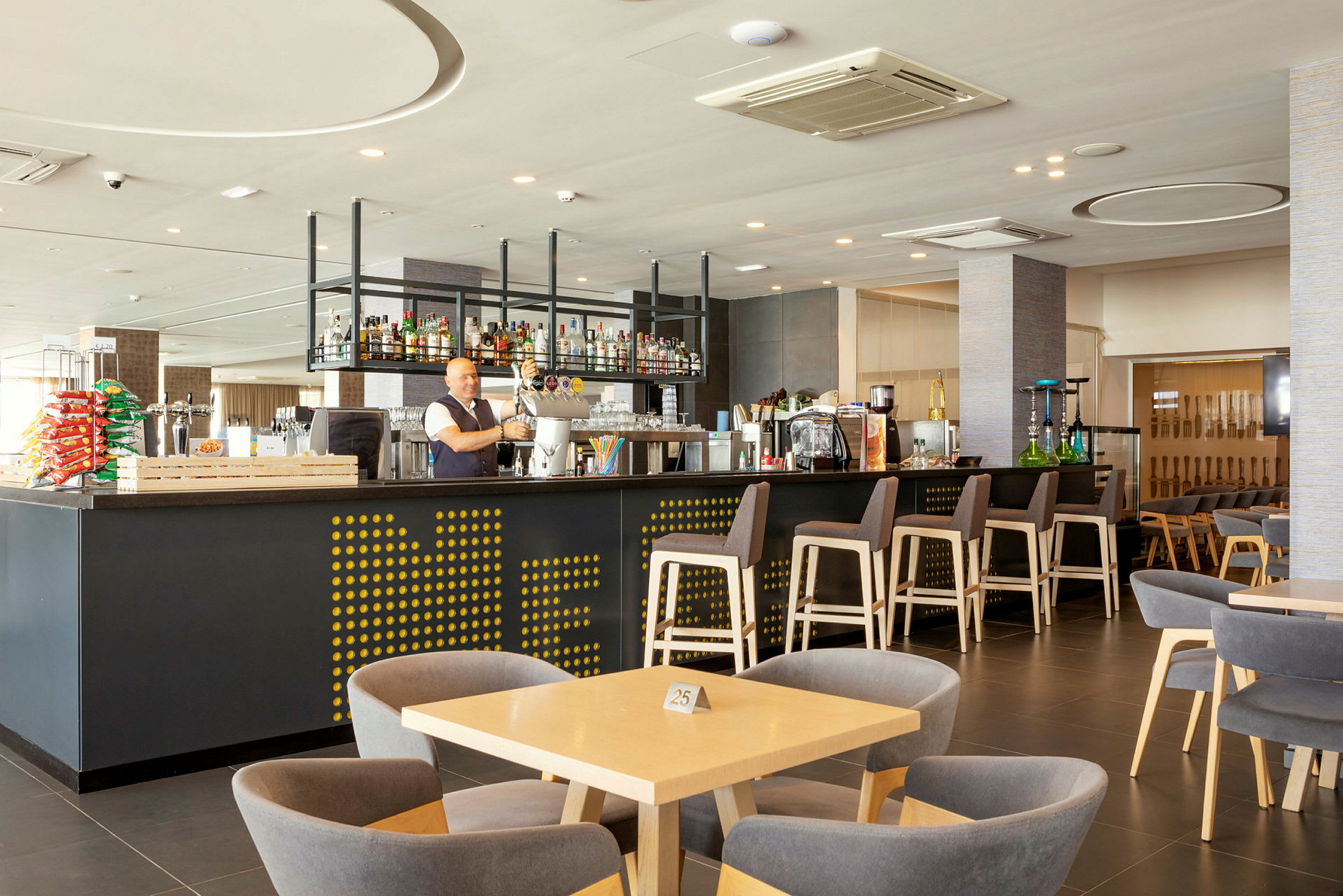 Interiør av en moderne bar med sitteplasser og belysning. (AI-generert tekst)