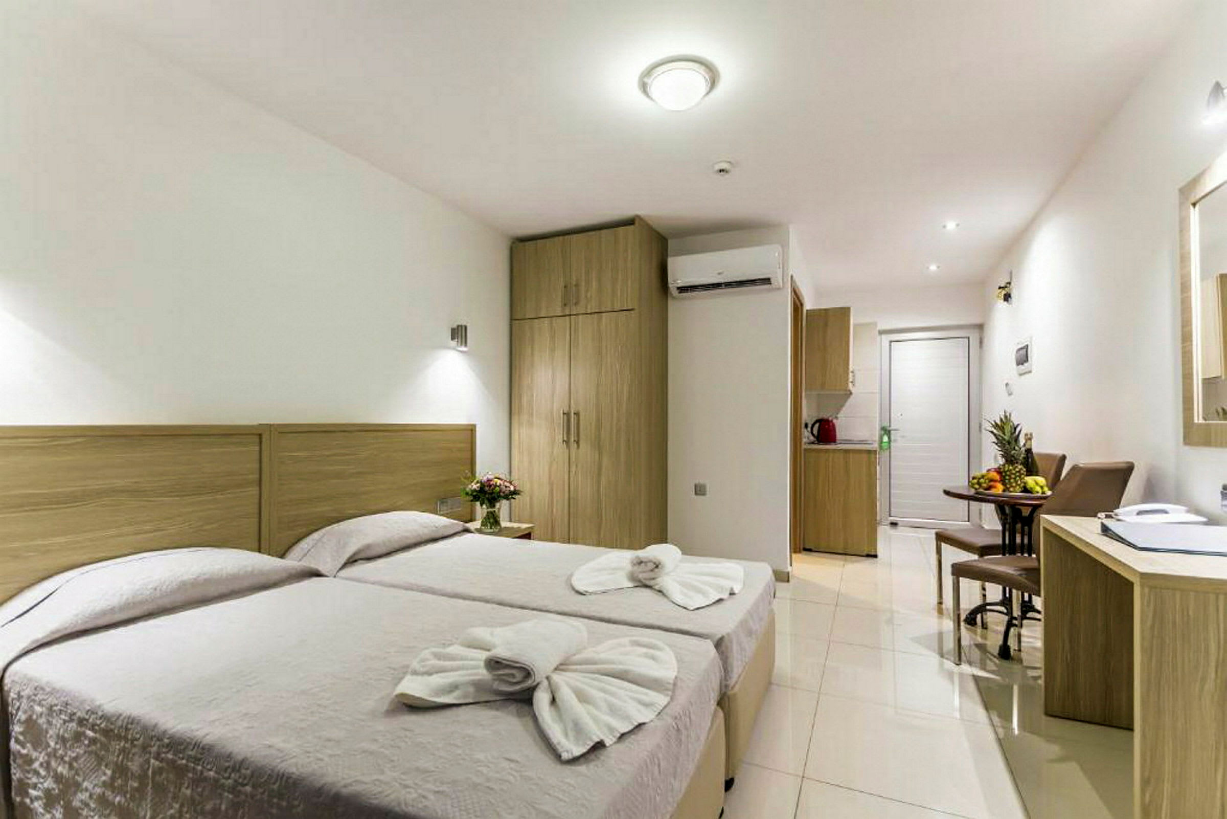 Hotellrom med to enkeltsenger, et bord med stoler og et skrivebord. (AI-generert tekst)