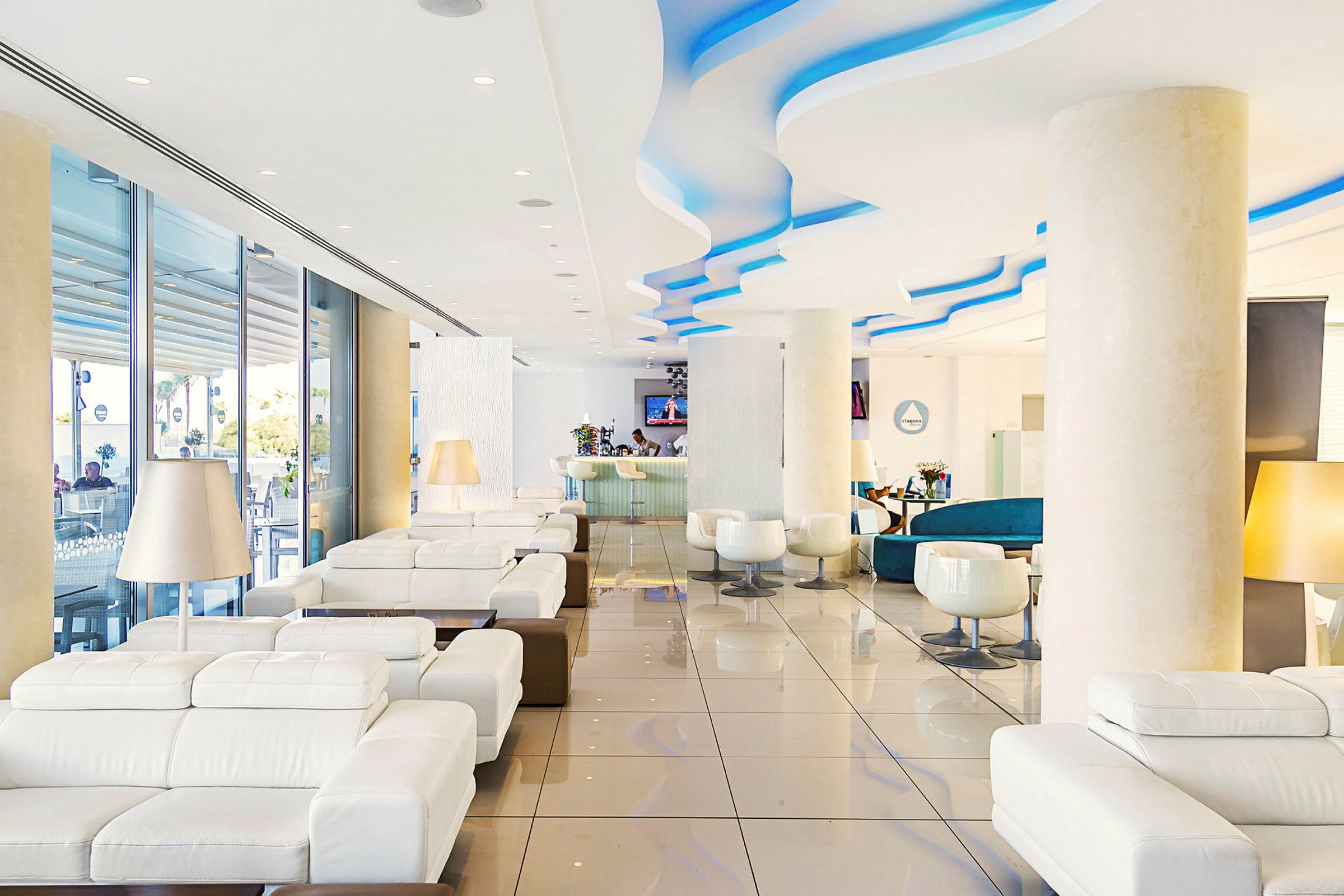 Hotellobby med hvite sofaer og, i bakgrunnen, en resepsjon. (AI-generert tekst)