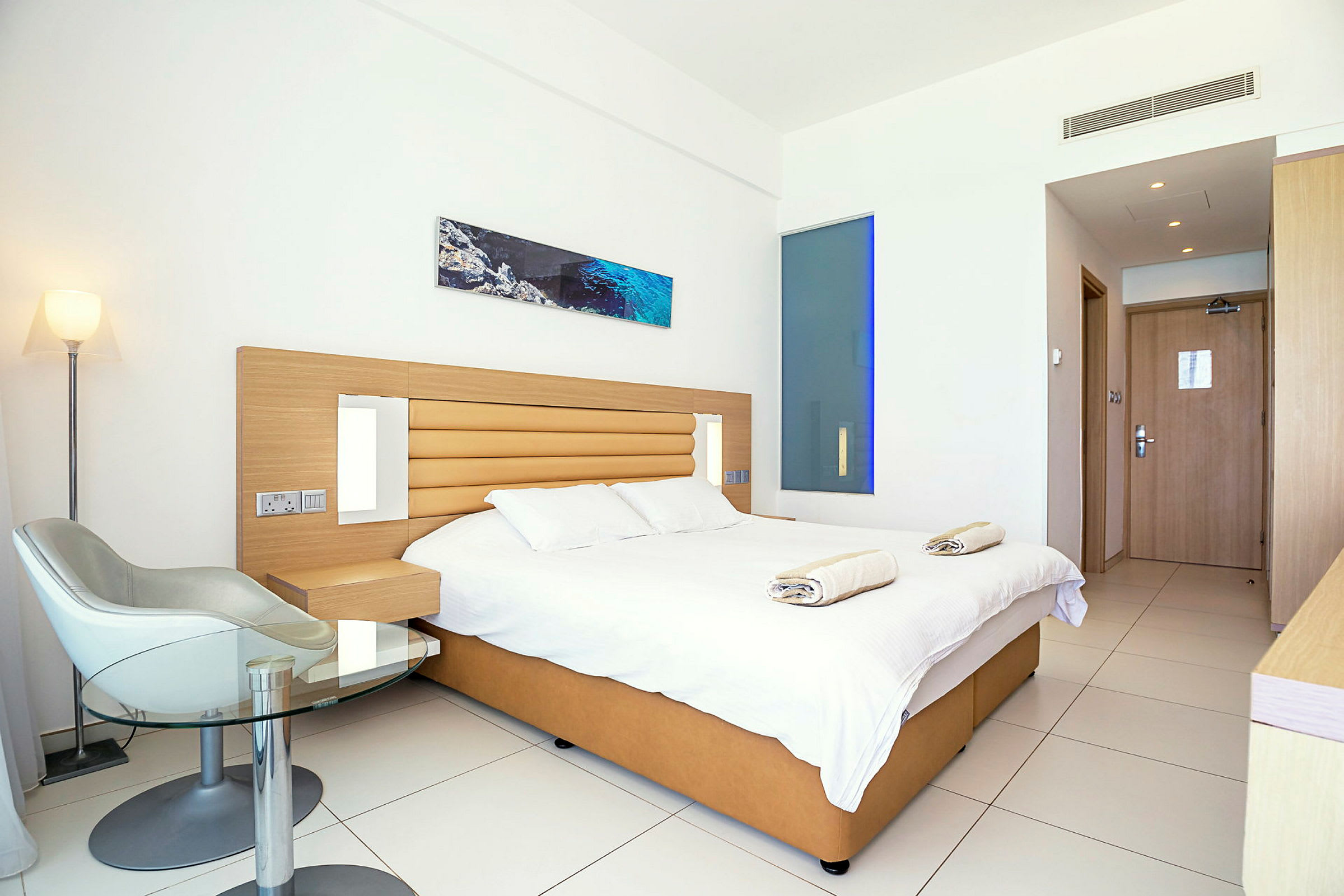 Moderne hotellrom med dobbeltseng, stol og bord. (AI-generert tekst)