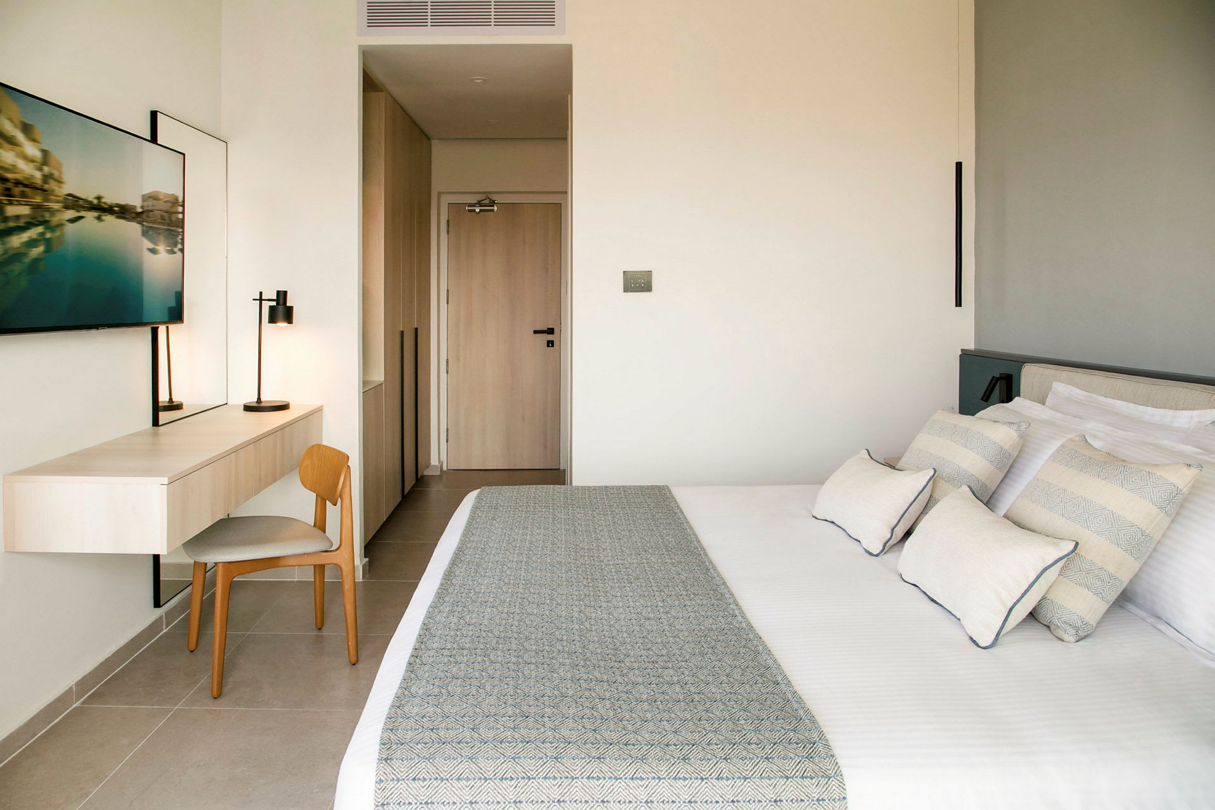 Moderne hotellrom med seng, skrivebord, stol og TV. (AI-generert tekst)