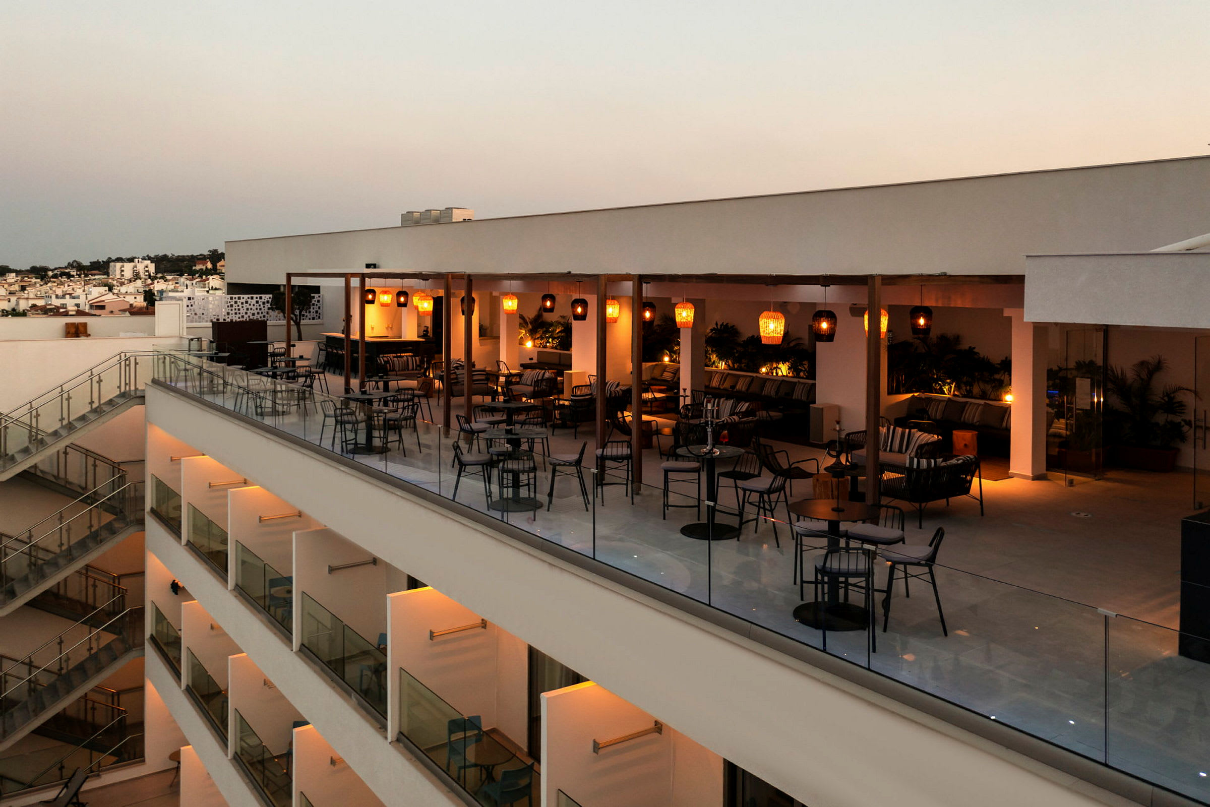 En takterrasse med sittegrupper og belysning under skumringen. (AI-generert tekst)