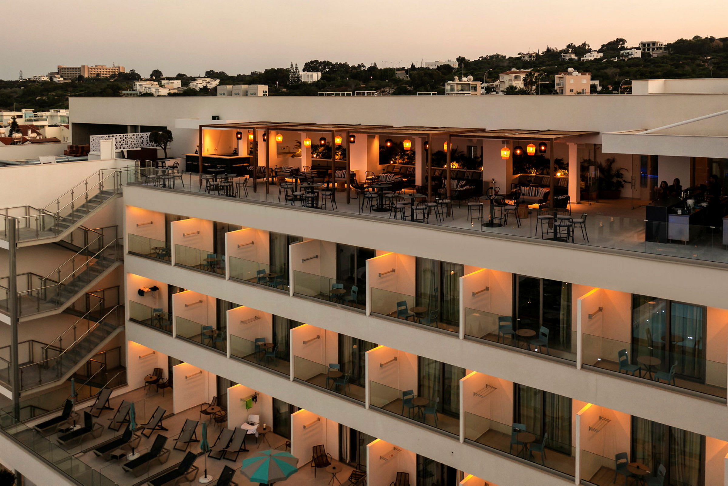 En hotellbygning med en opplyst terrasse og balkonger. (AI-generert tekst)