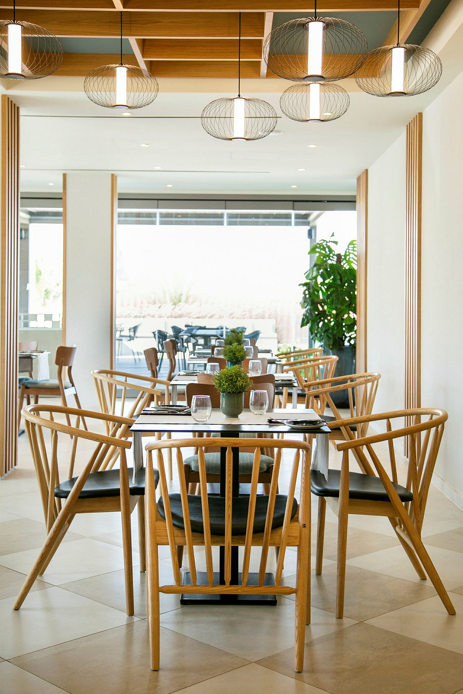 En restaurant med trestoler og bord samt dekorative lamper i taket. (AI-generert tekst)