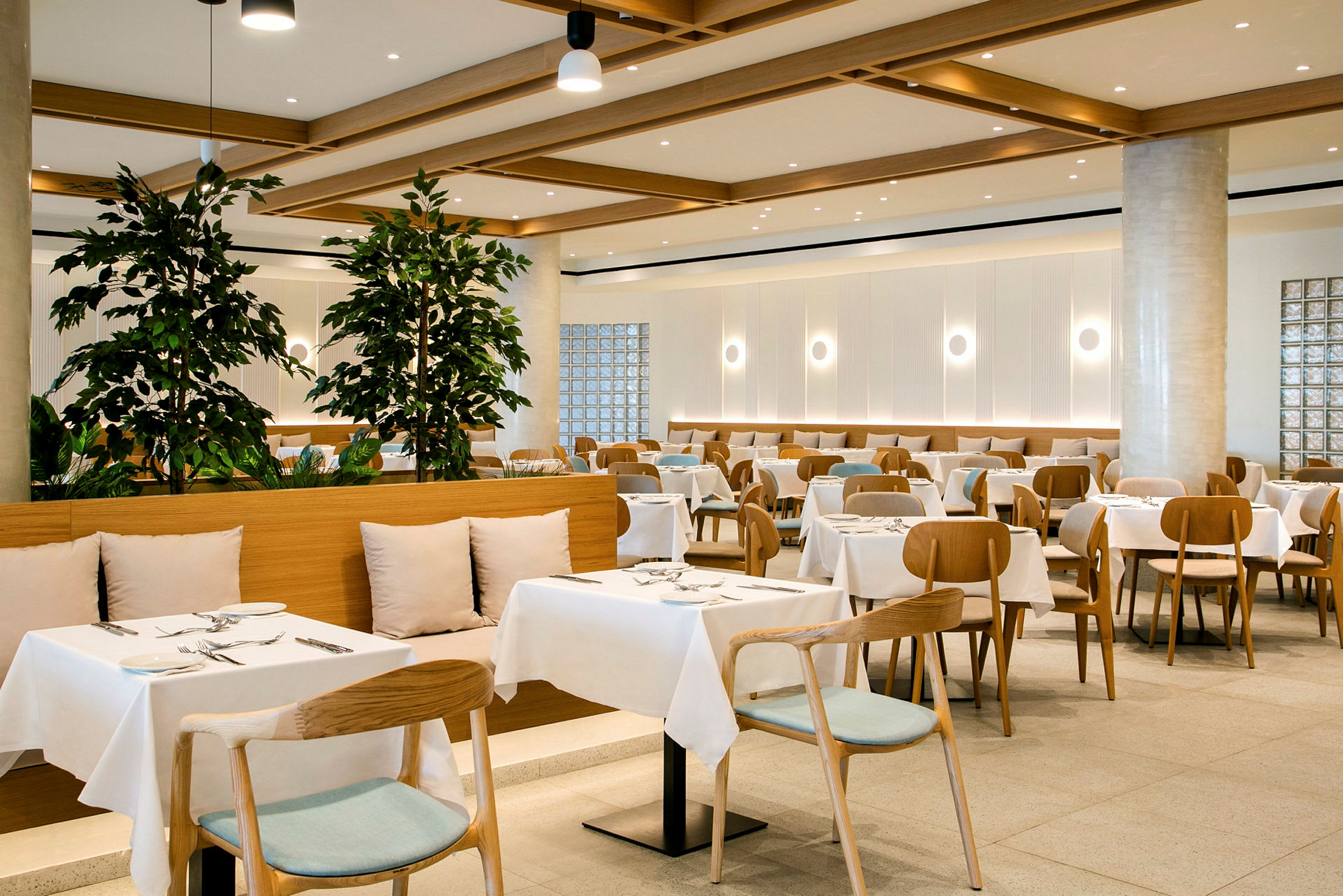 En moderne restaurant med oppsatte bord og stoler, dekorert med grønne planter. (AI-generert tekst)