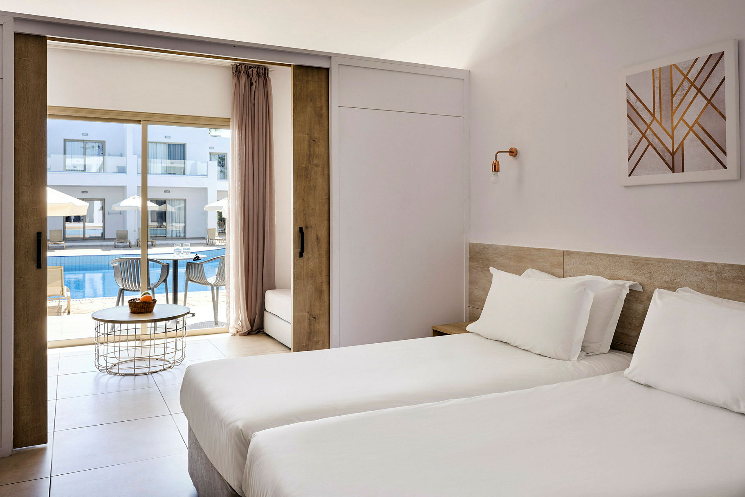 Hotellrom med to enkeltsenger og utsikt mot et utendørs basseng og solsenger. (AI-generert tekst)