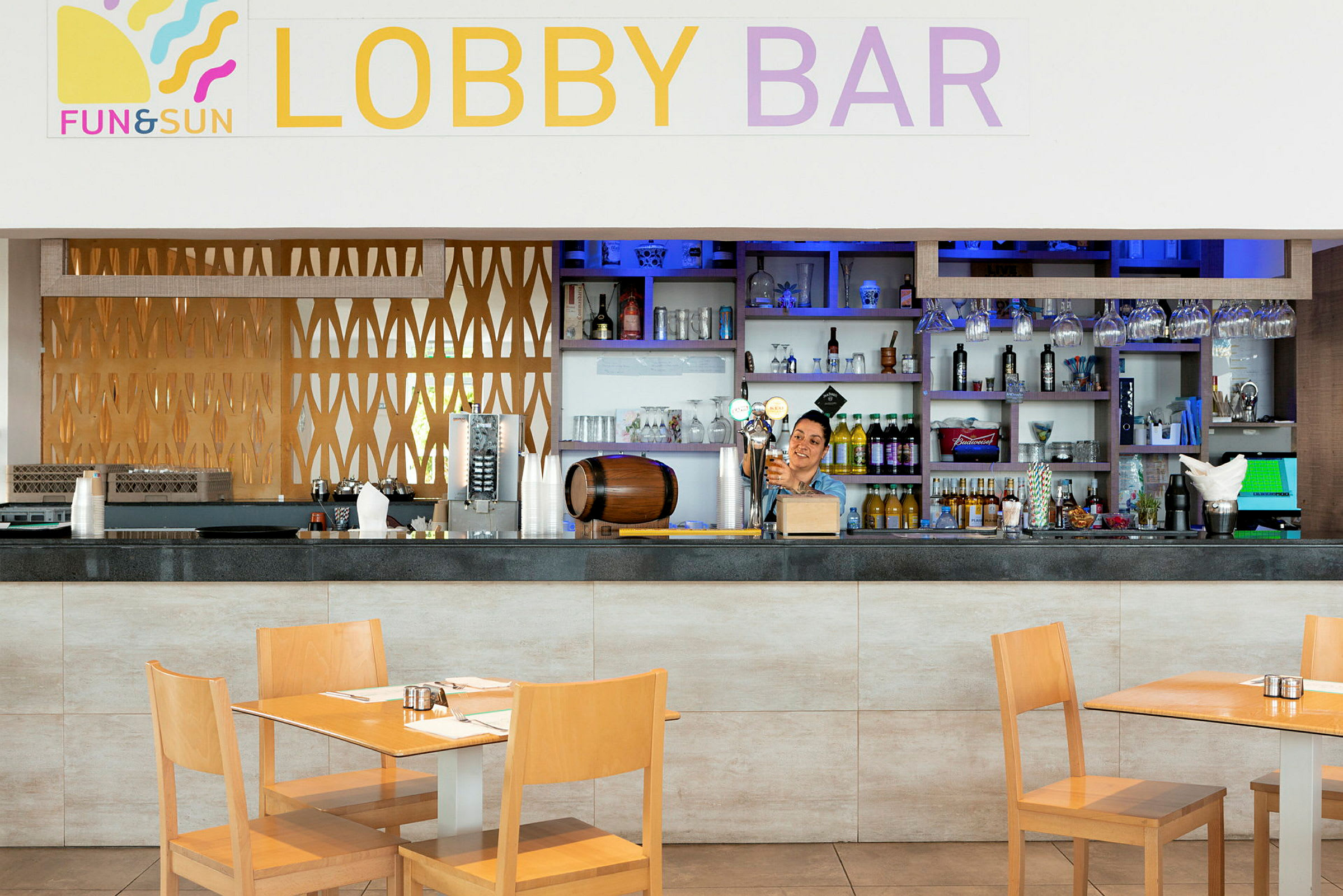 Lobbybaren med bord og stoler, samt hyller med flasker og glass bak bardisken. (AI-generert tekst)