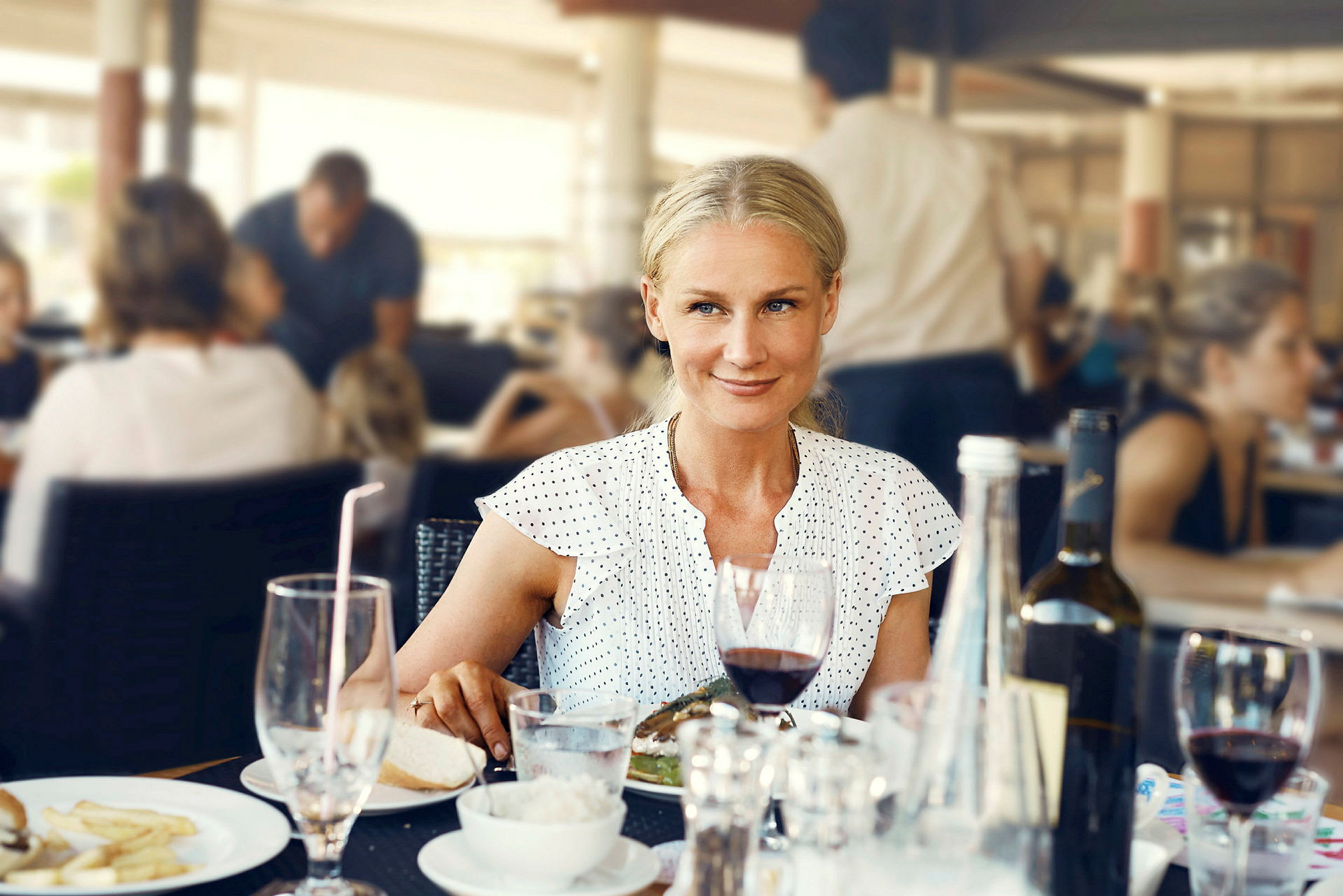 En person sitter ved et bord på en restaurant med forskjellige drikker og mat servert. (AI-generert tekst)
