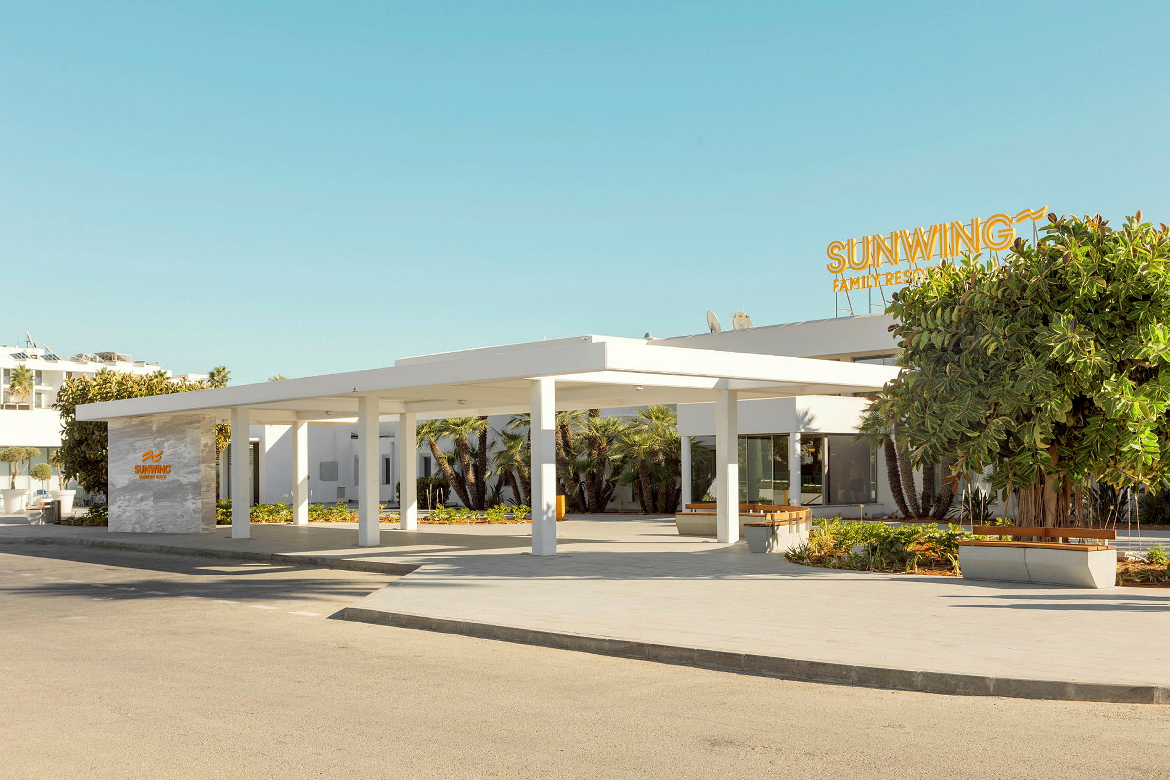Bilde av inngangen til et moderne hotell med en hvit fasade og et skilt med påskriften Sunwing Family Resort. (AI-generert tekst)