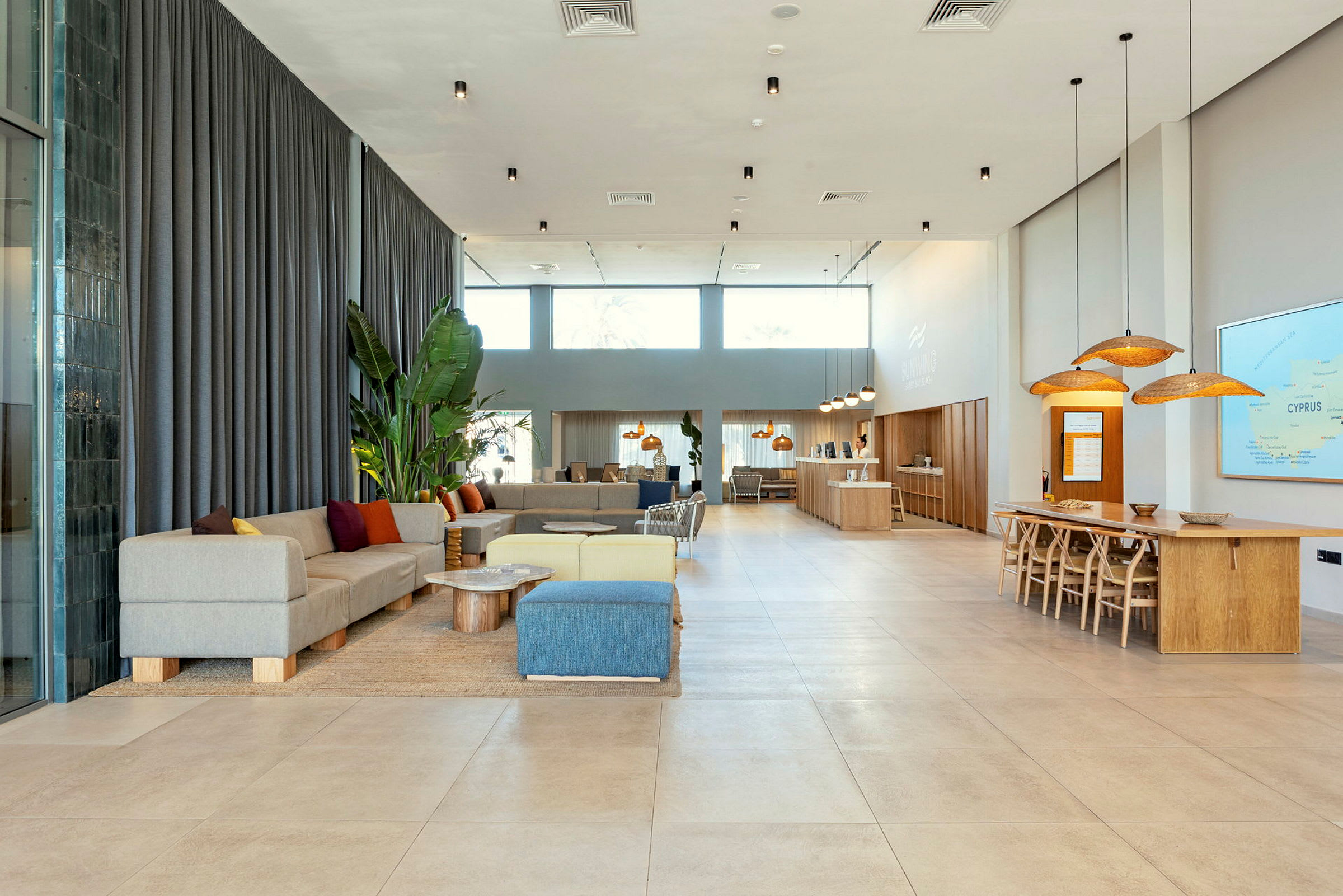 Et moderne og lyst innredet hotellobbyområde med sitteplasser, bord og en resepsjon. (AI-generert tekst)