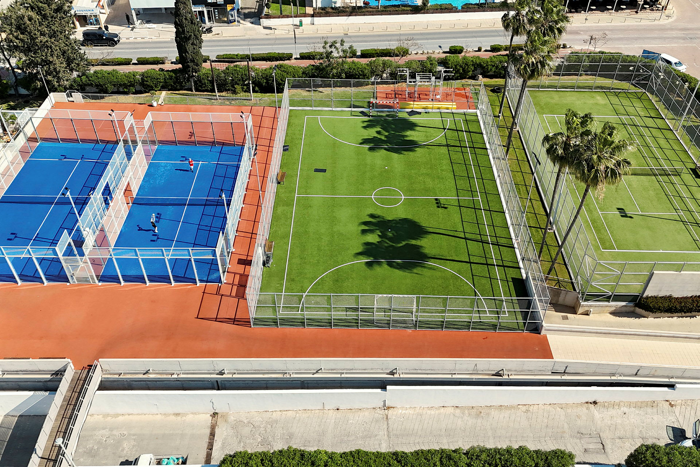 Bilde av flere utendørs baner, inkludert en blå tennis- eller padelbane og en grønn fotballbane. (AI-generert tekst)
