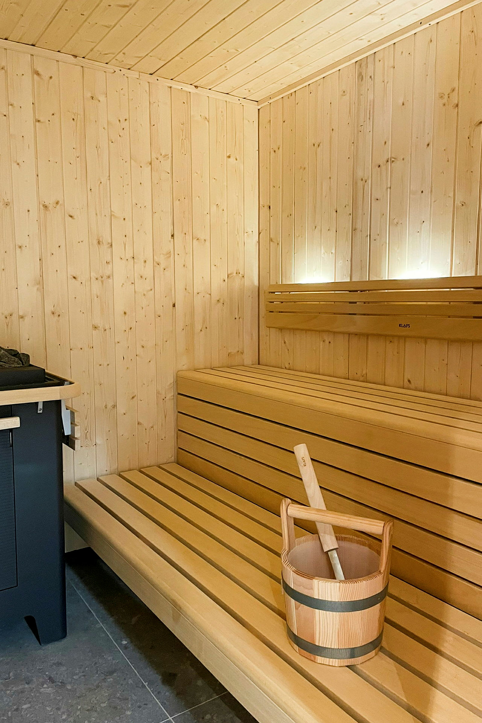 En badstue med trepaneler, en trebenk og en bøtte med øse for damp. (AI-generert tekst)
