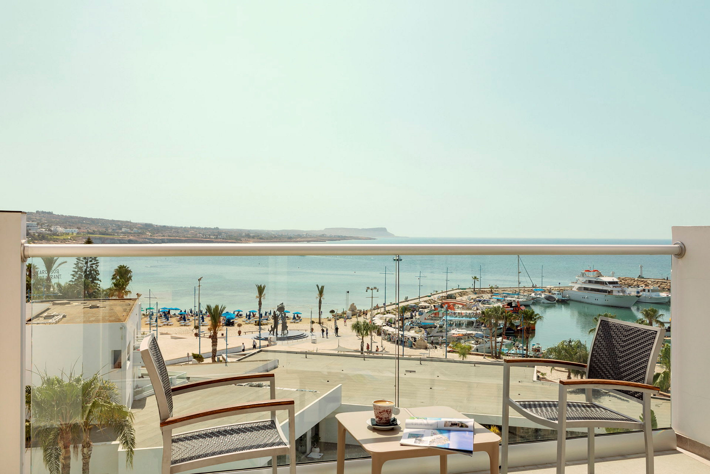 Utsikt fra en hotellbalkong over en marina og havet. (AI-generert tekst)