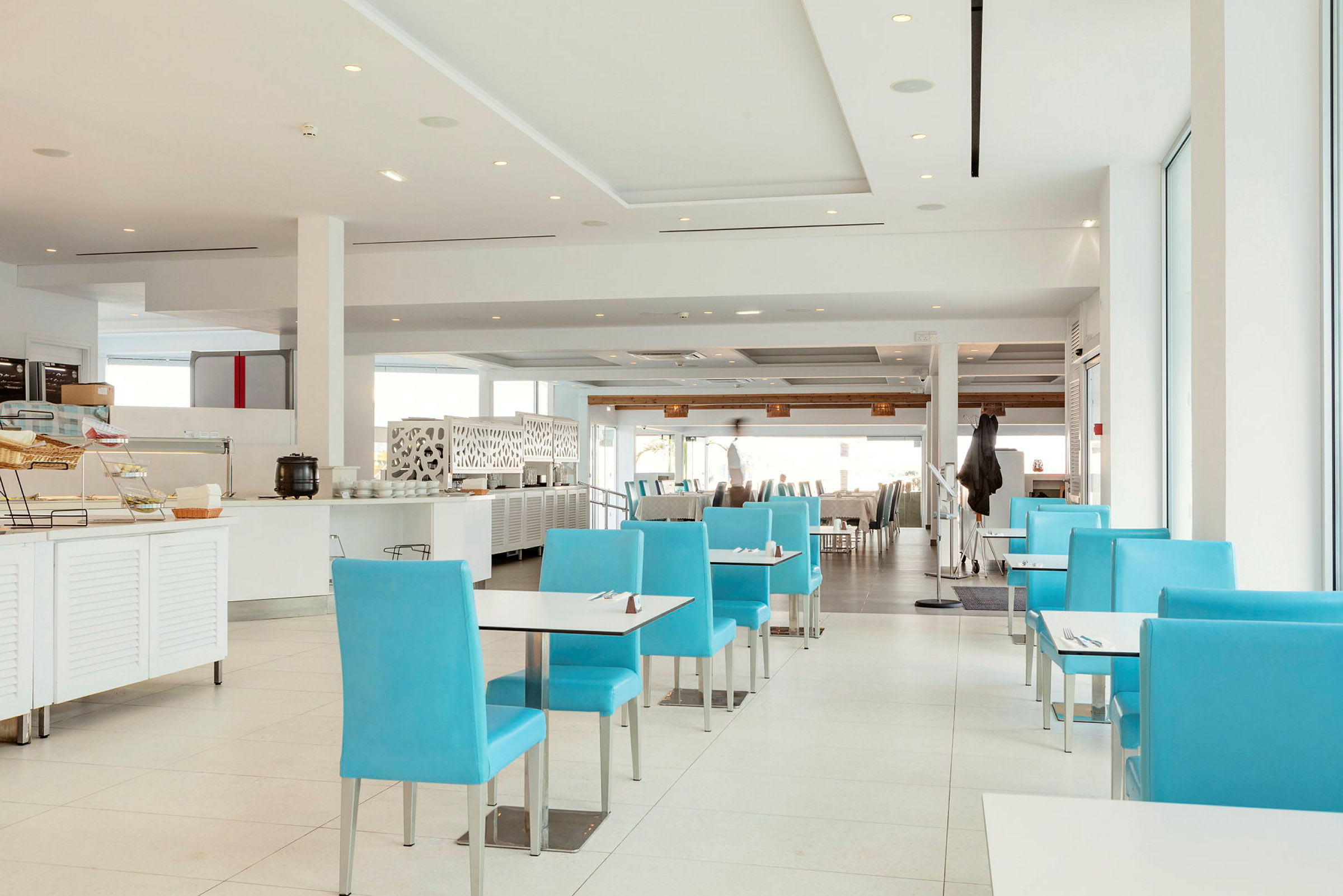 Bilde av en moderne restaurant med blå stoler og hvit innredning. (AI-generert tekst)