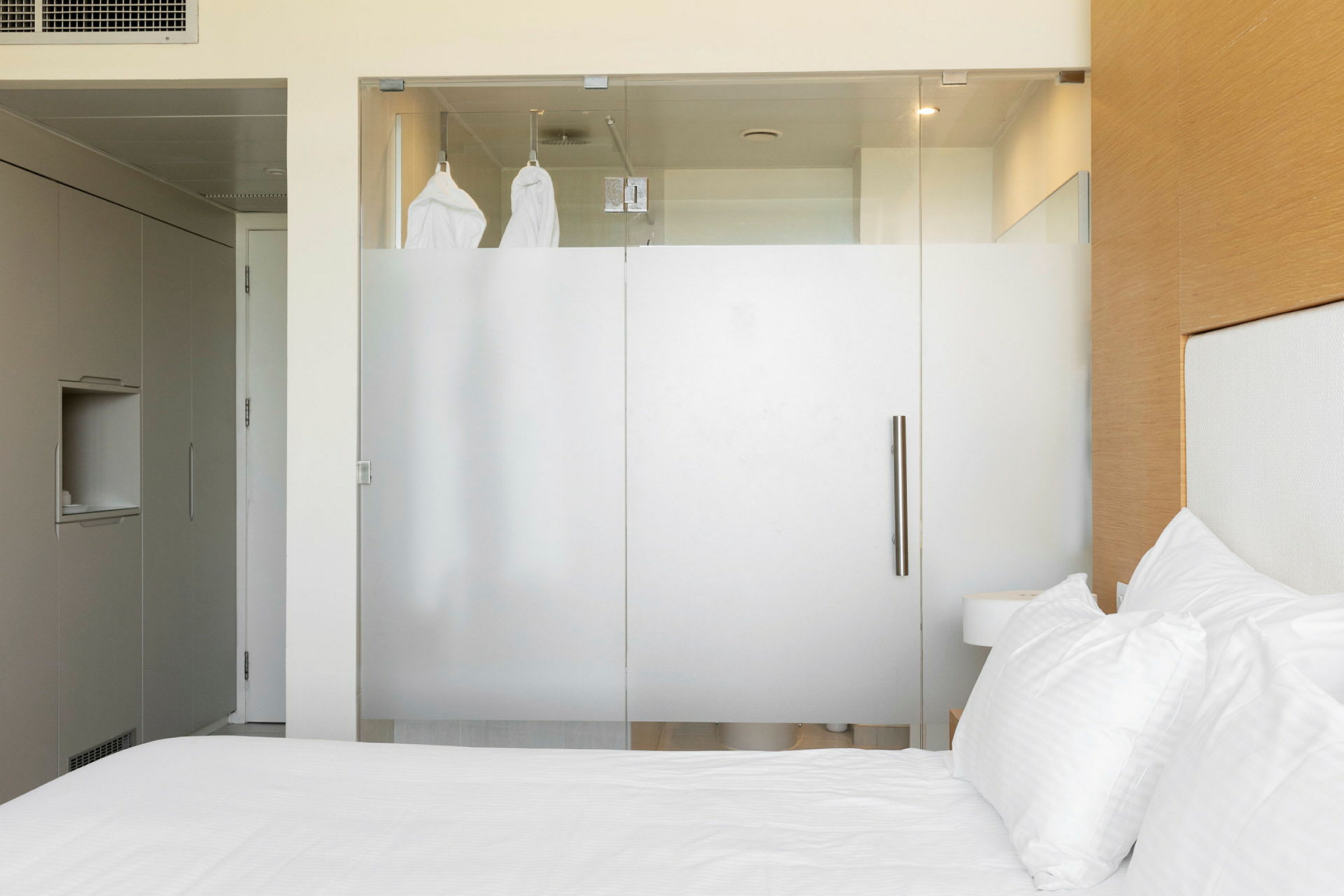 Et hotellrom med en glassvegg som deler av badet. (AI-generert tekst)