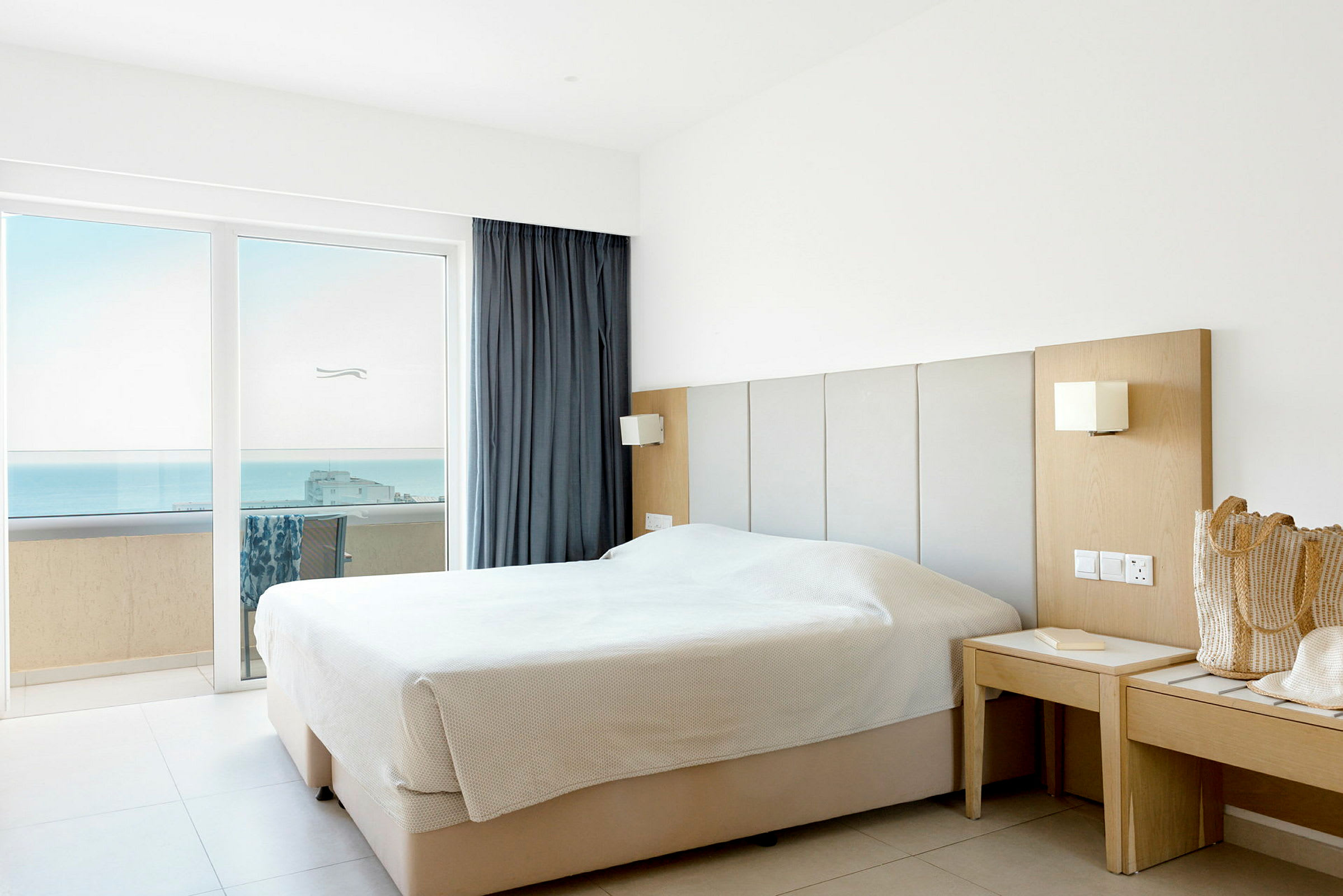 Et hotellrom med en dobbeltseng nær vinduet med utsikt over havet. (AI-generert tekst)