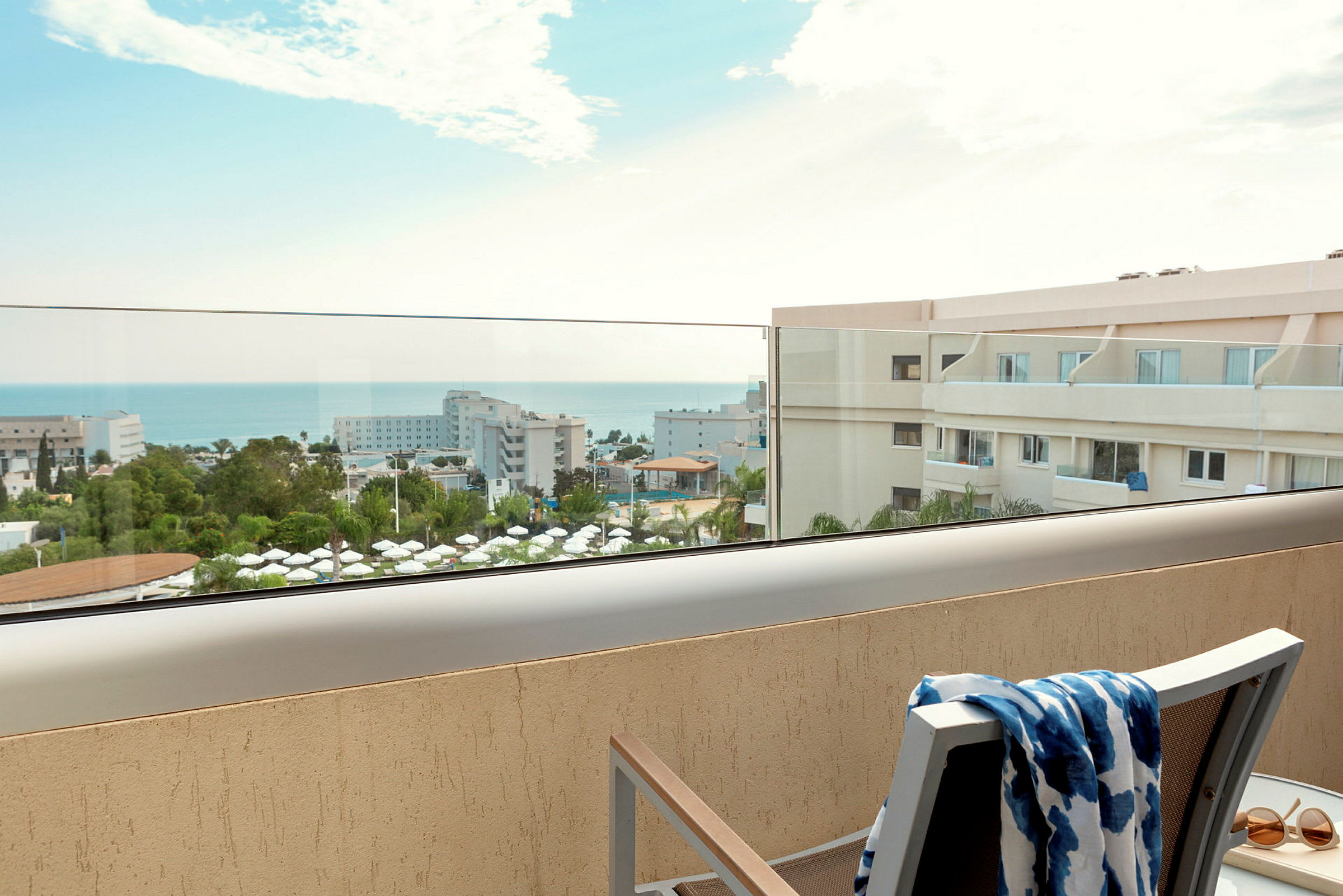 Utsikt fra balkong over hotellområde og hav. (AI-generert tekst)