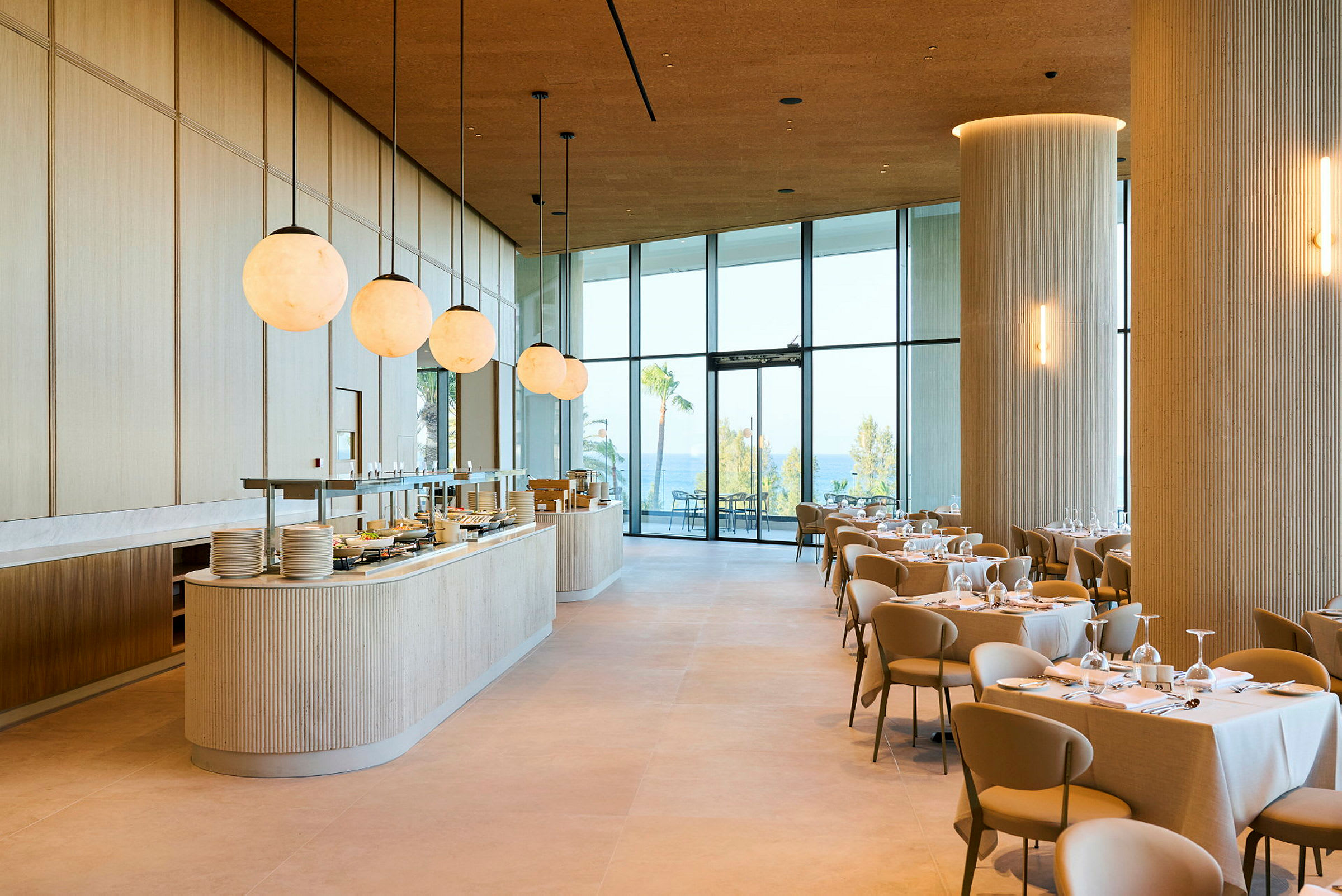 Et moderne og lyst restaurantområde med dekkede bord og store vinduer som vender ut mot en utendørsutsikt. (AI-generert tekst)