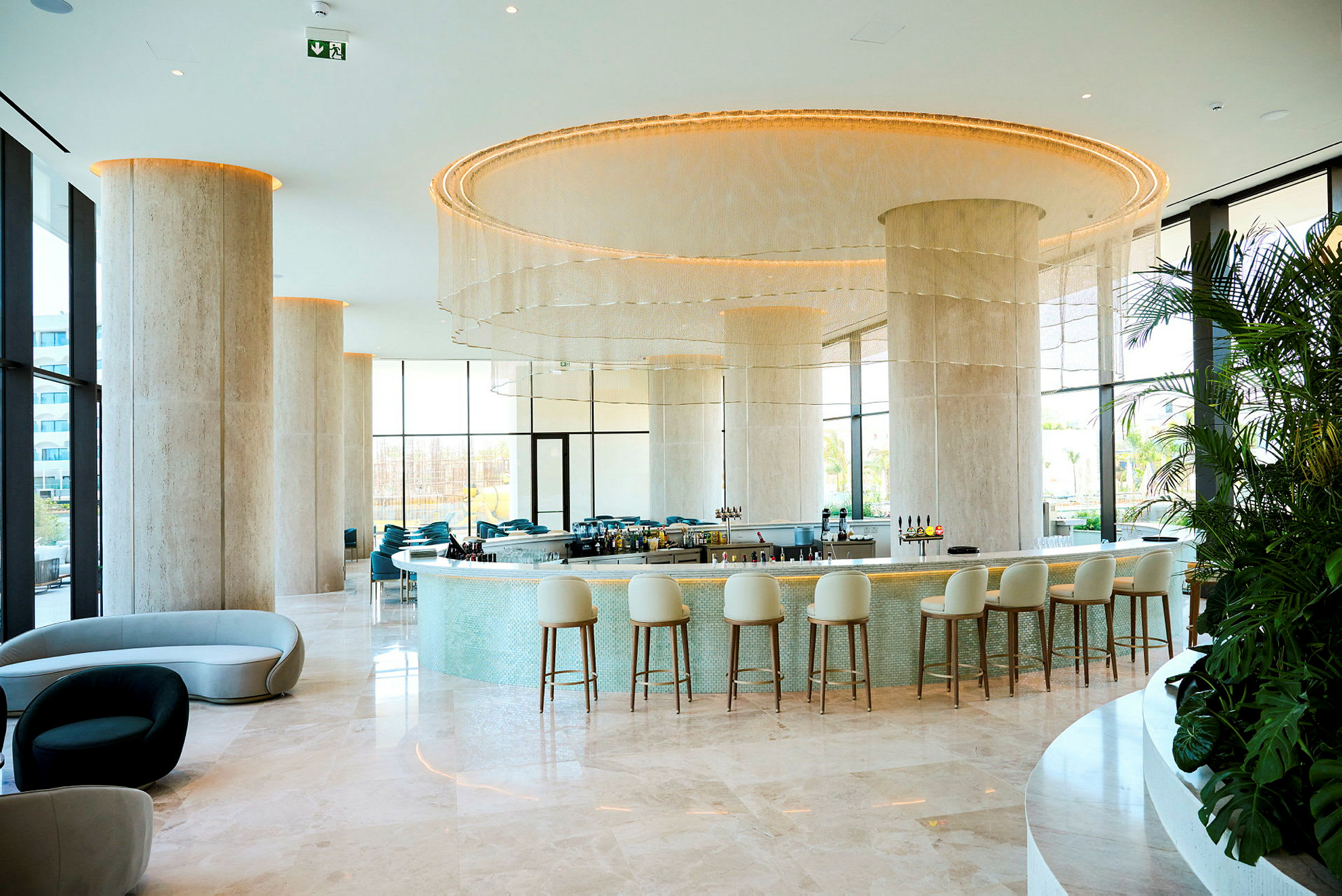 En elegant hotellbar med moderne innredning, høye stoler og lyse farger. (AI-generert tekst)