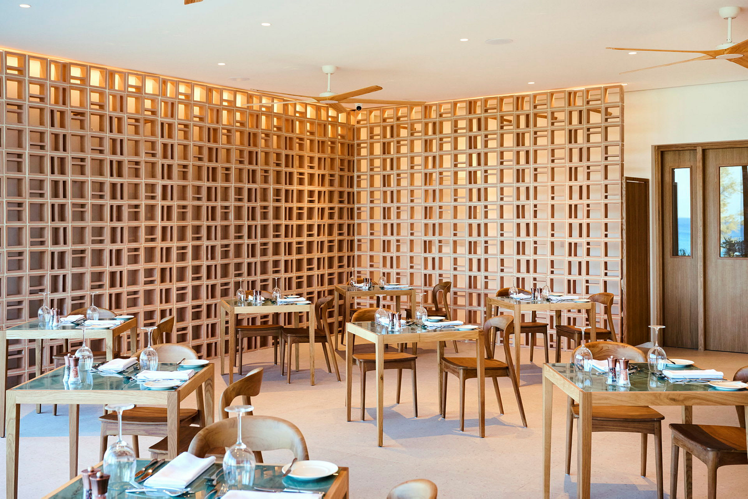 Et moderne restaurantområde med trebord og stoler samt en dekorativ gitterliknende trevegg. (AI-generert tekst)