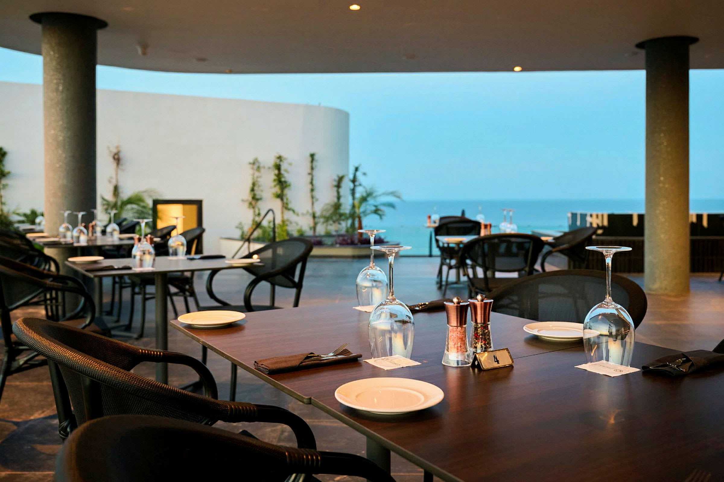 Restaurant med bord dekket på en terrasse med utsikt over havet. (AI-generert tekst)