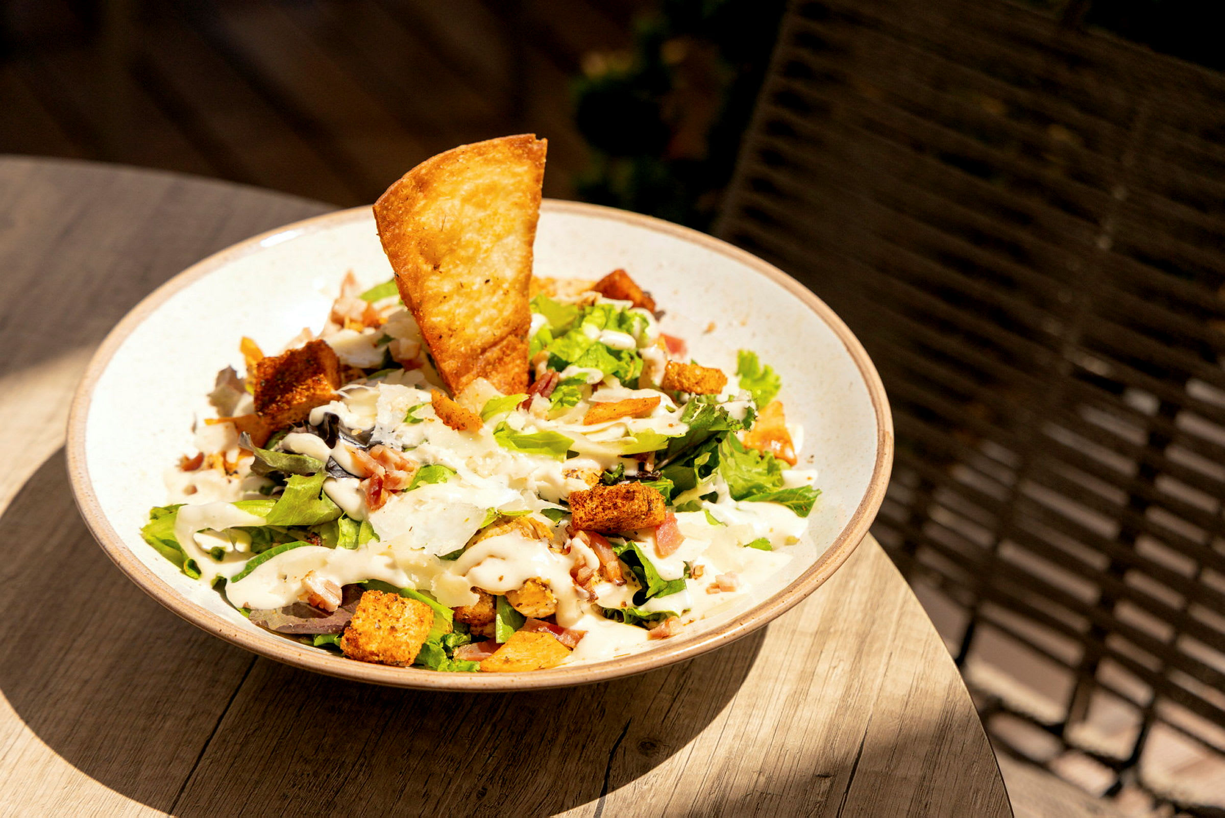 En bolle med salat som inneholder grønnsaker, krutonger, et sprøtt brød og dressing. (AI-generert tekst)