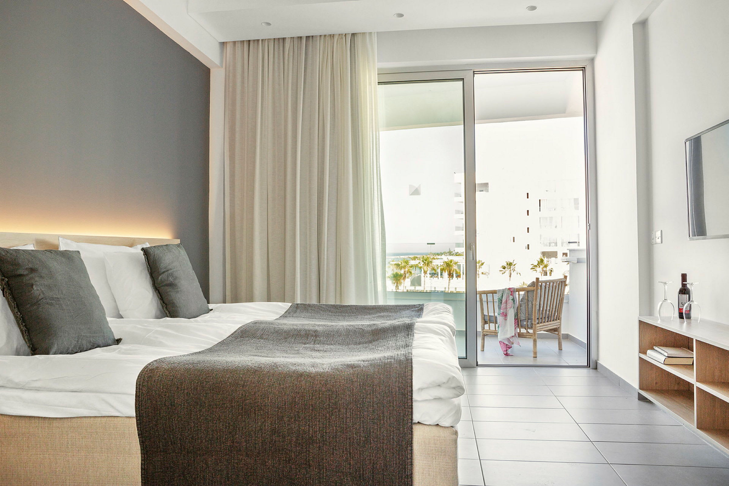 Moderne hotellrom med dobbeltseng, balkong og sittegruppe. (AI-generert tekst)