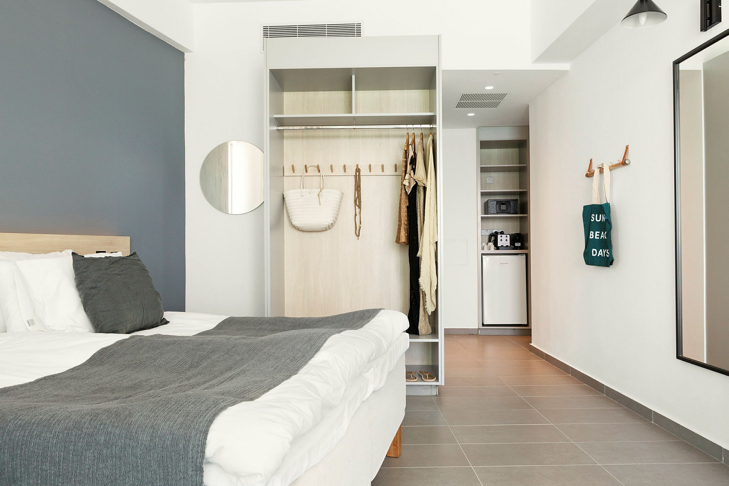 Moderne hotellrom med seng, garderobe og lite kjøkken. (AI-generert tekst)