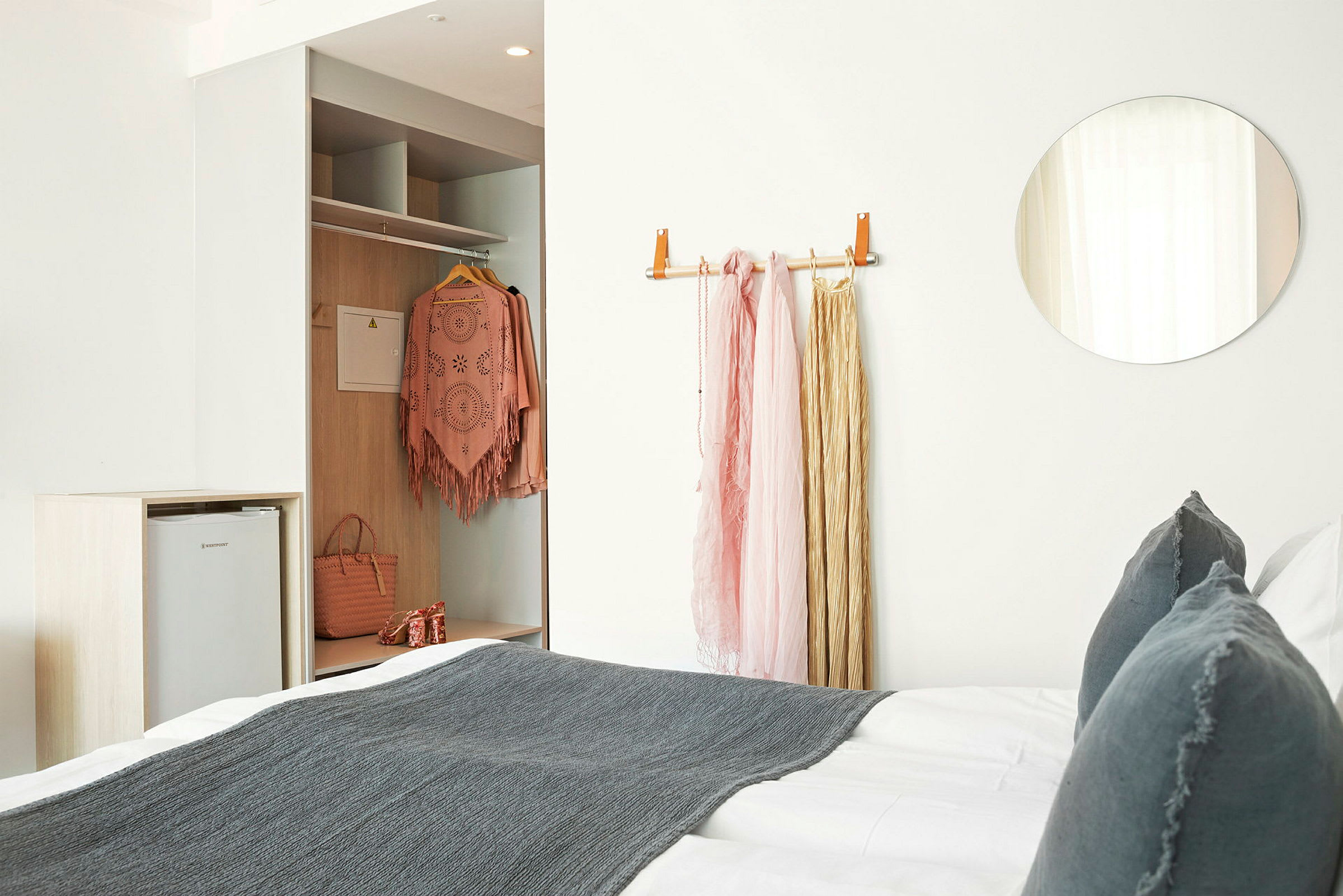 Et hotellrom med en seng og garderobe; klær er hengt opp. (AI-generert tekst)