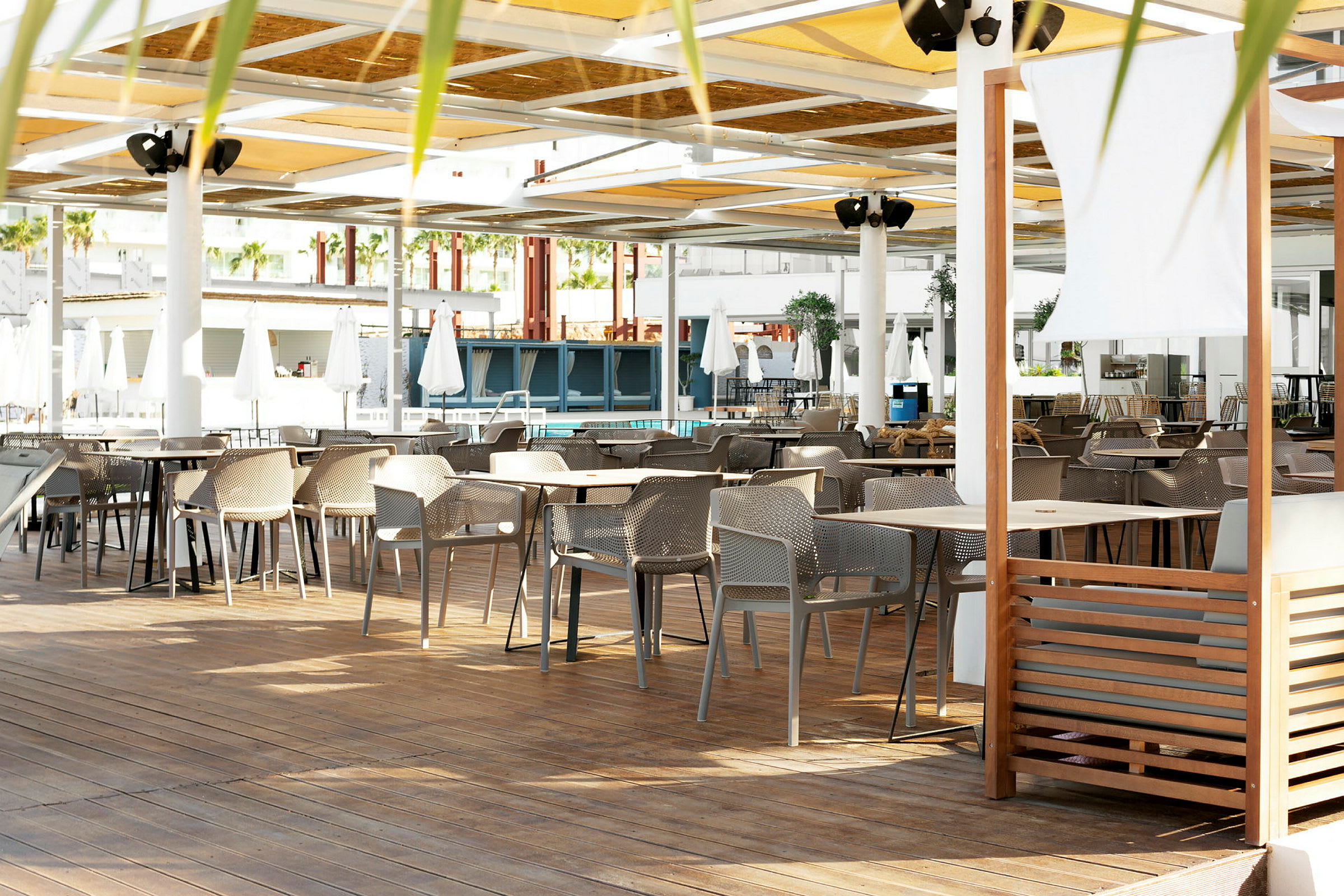 En sittegruppe med bord og stoler på en terrasse med tak. (AI-generert tekst)