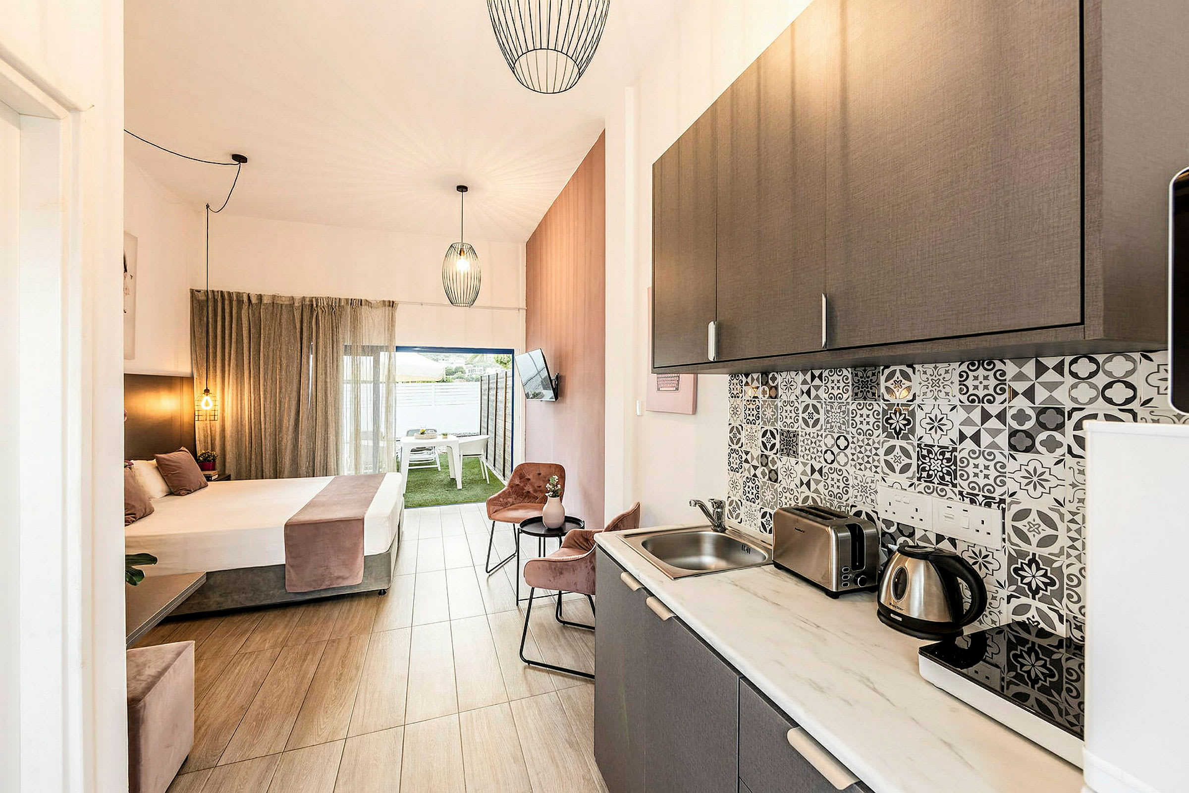 Bilde av et hotellrom med kjøkken og soveområde, lyse møbler og elegant interiør. (AI-generert tekst)
