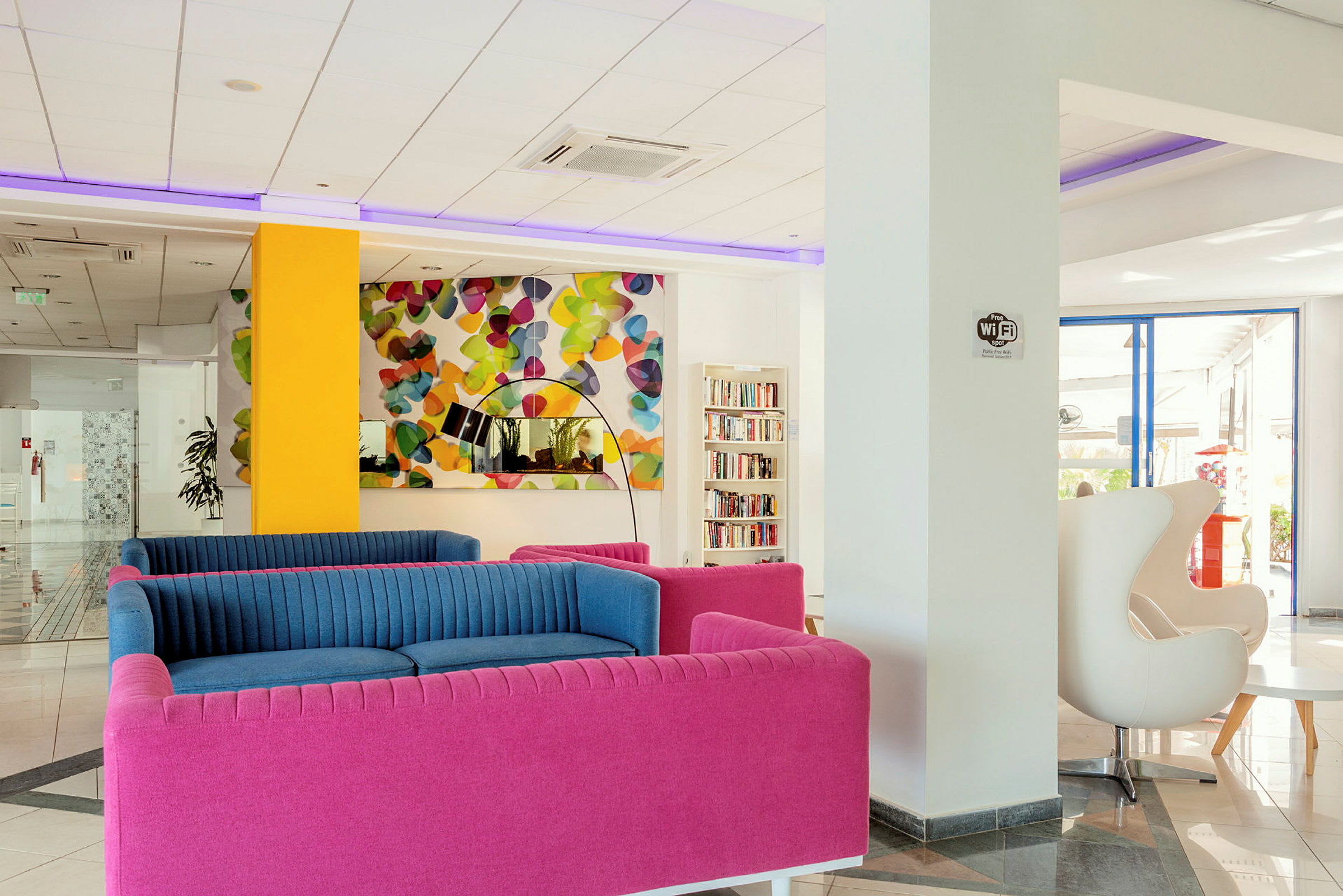En moderne lobby med fargerike sofaer og et fargerikt kunstverk. (AI-generert tekst)