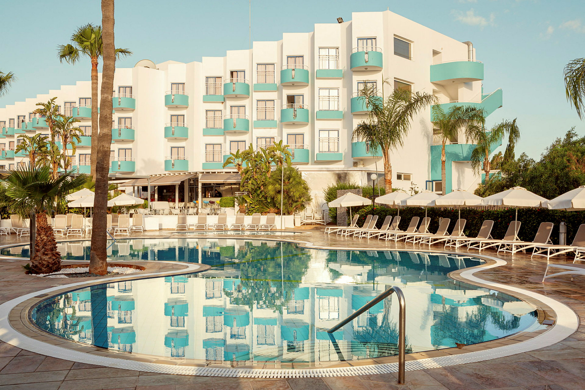 Hotell med moderne design og basseng i forgrunnen. (AI-generert tekst)