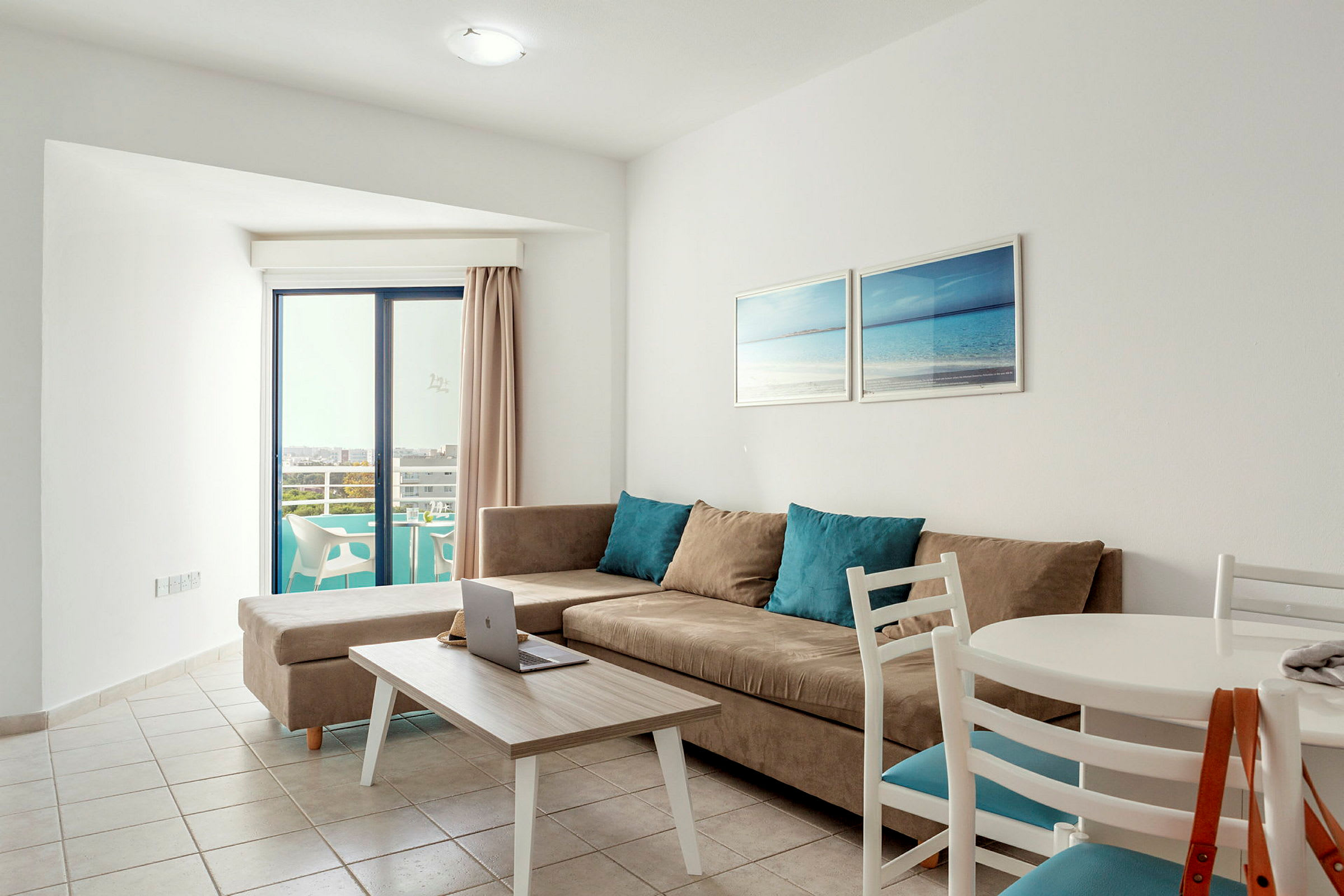 Lyst innredet stue med sofa, spisebord og utsikt mot en balkong. (AI-generert tekst)