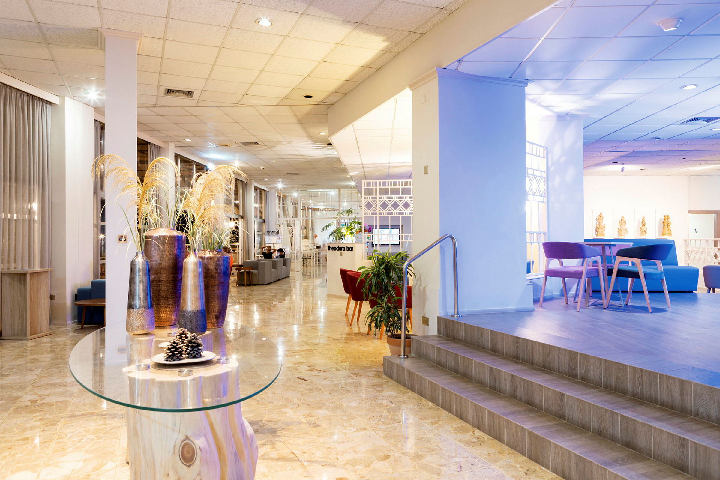 Bilde av en hotellobby med moderne møbler og dekorasjoner. Et bord med dekorative gjenstander og et forhøyet sitteområde er synlig. (AI-generert tekst)
