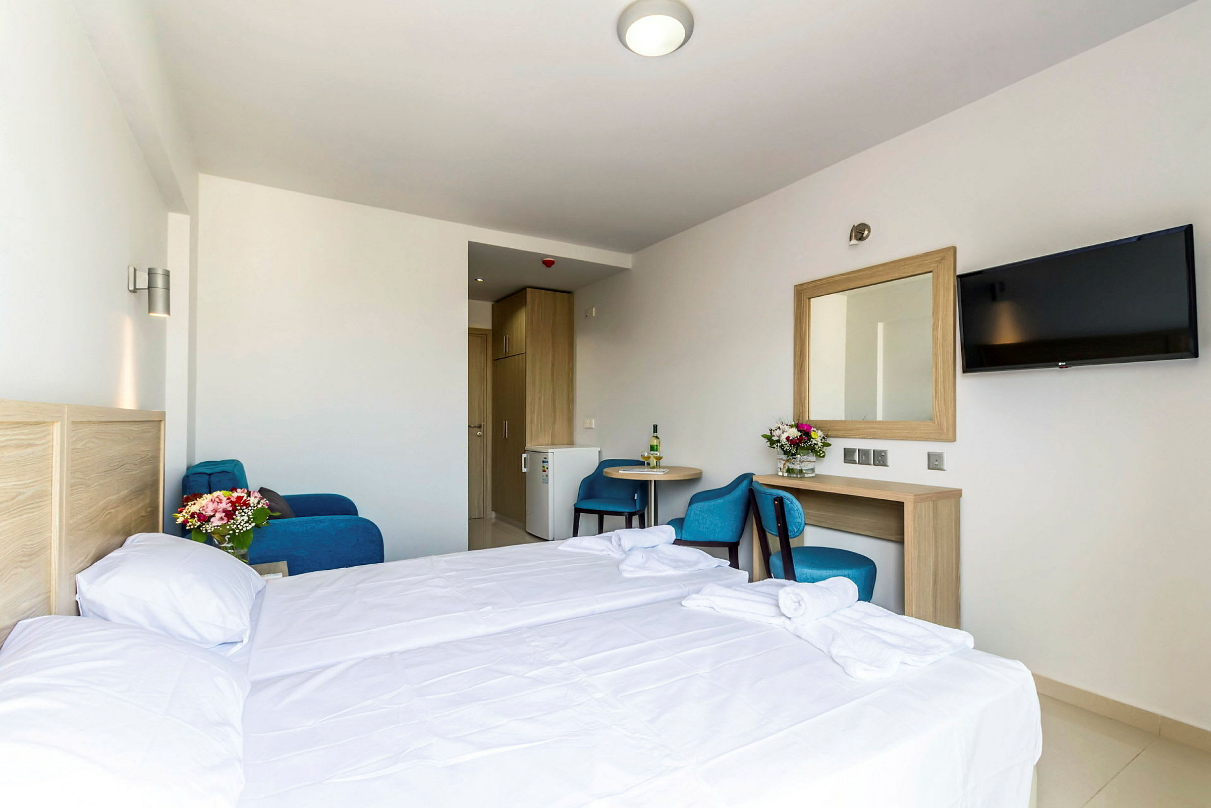 Hotellrom med seng, bord, stol, speil og TV. (AI-generert tekst)