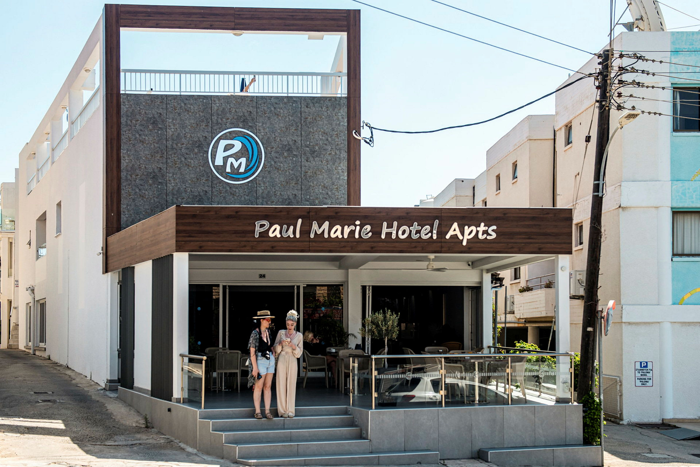 Forsiden av Paul Marie Hotel Apartments med uteservering og inngang. (AI-generert tekst)