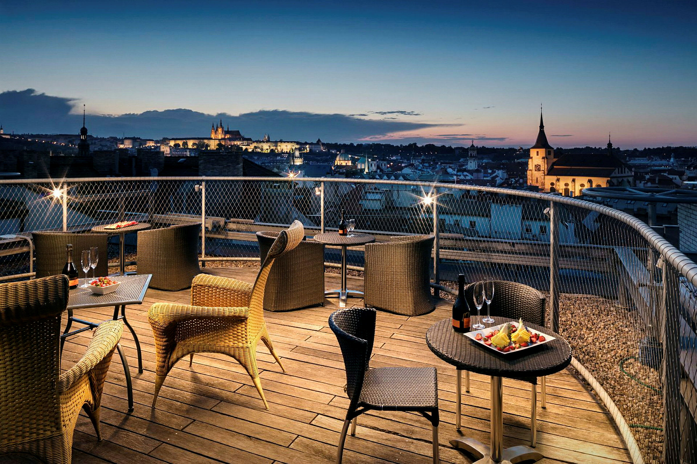 Terrasse med sitteplasser og utsikt over by ved solnedgang. (AI-generert tekst)